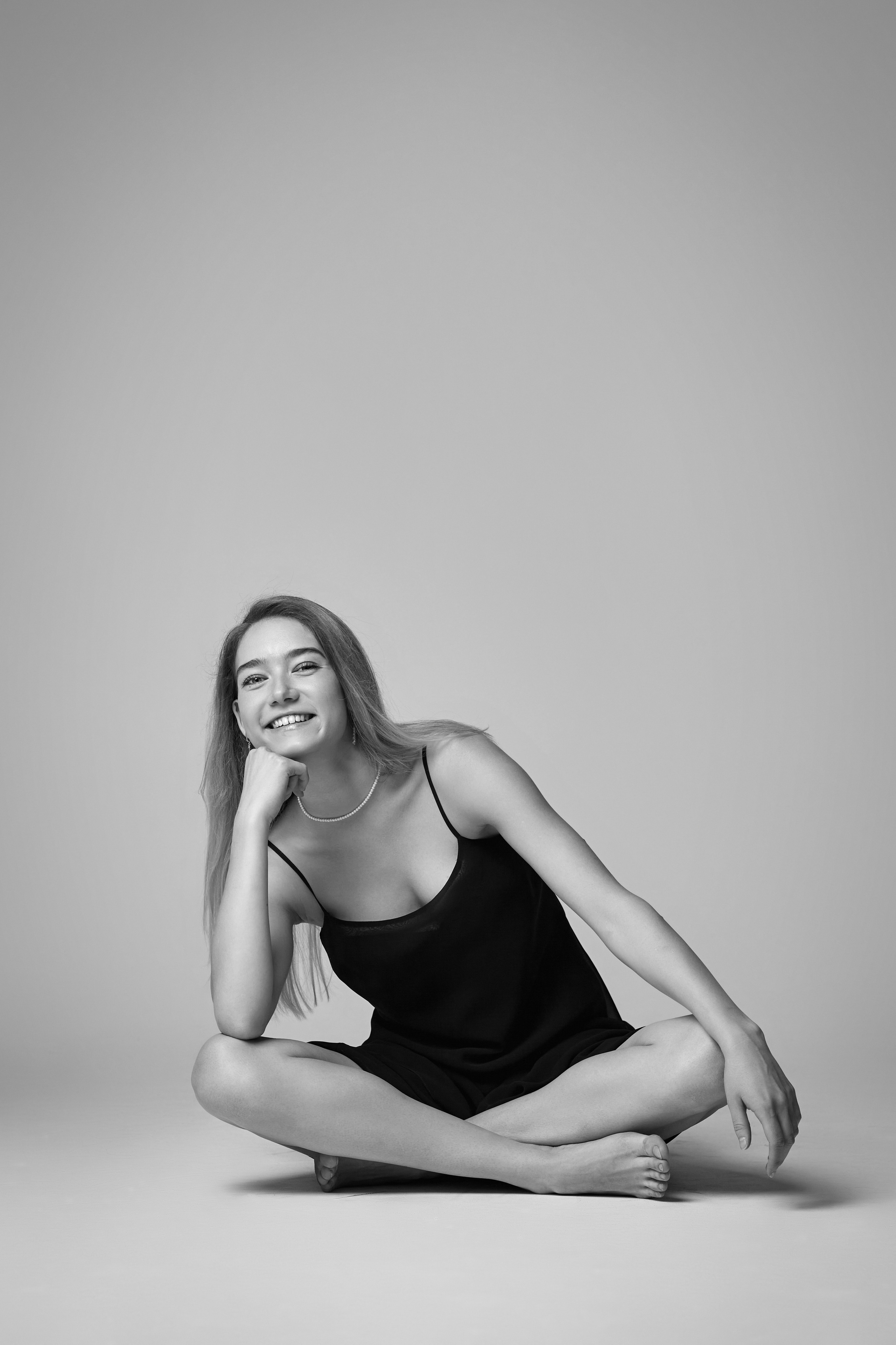 Светловолосая Алиса моделирует свою белоснежную рубашку, позируя на светлом фоне студии.