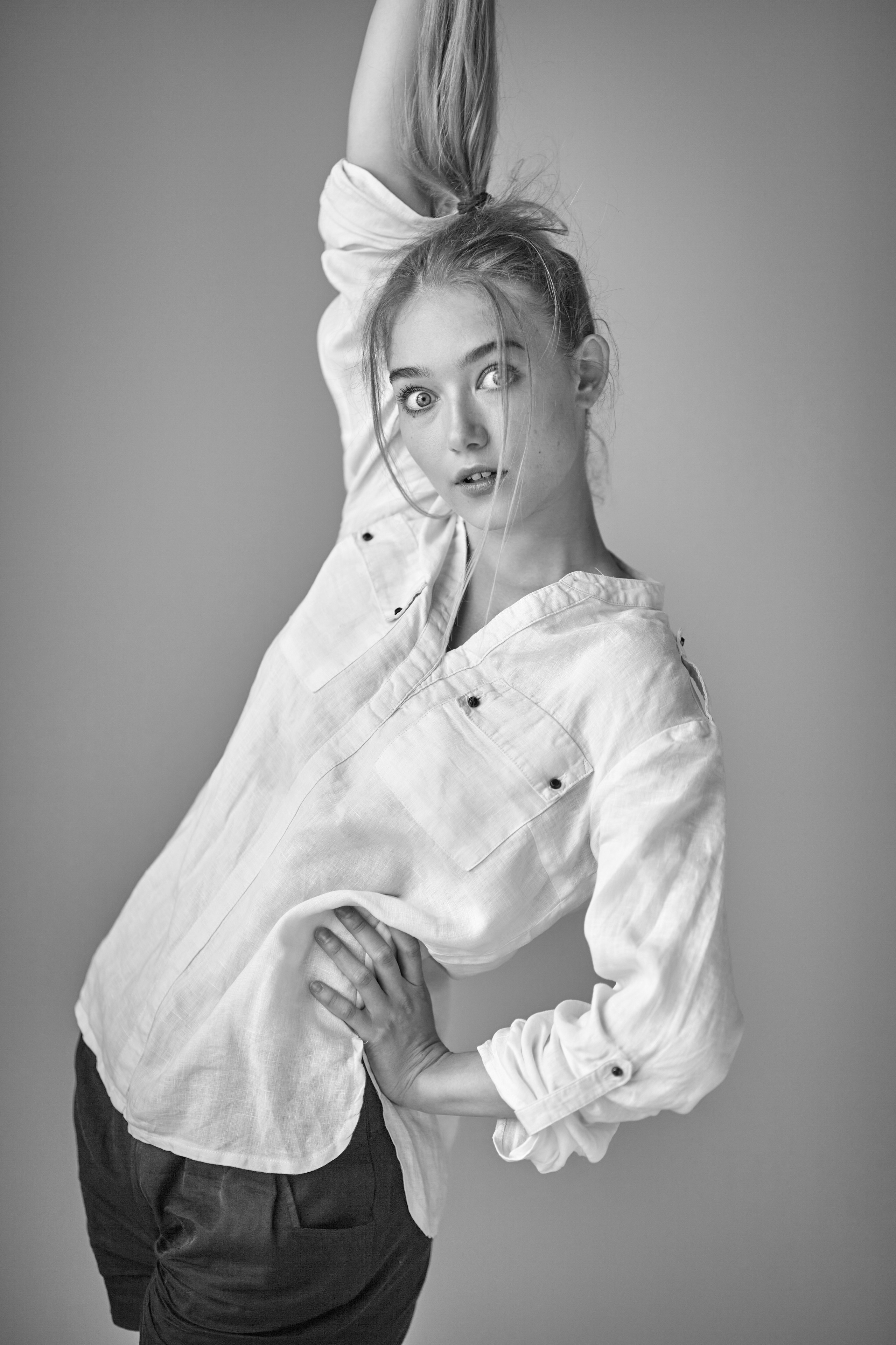 Светловолосая модель Алиса в студии на светлом фоне в рубашке и пиджаке, создавая деловой образ.