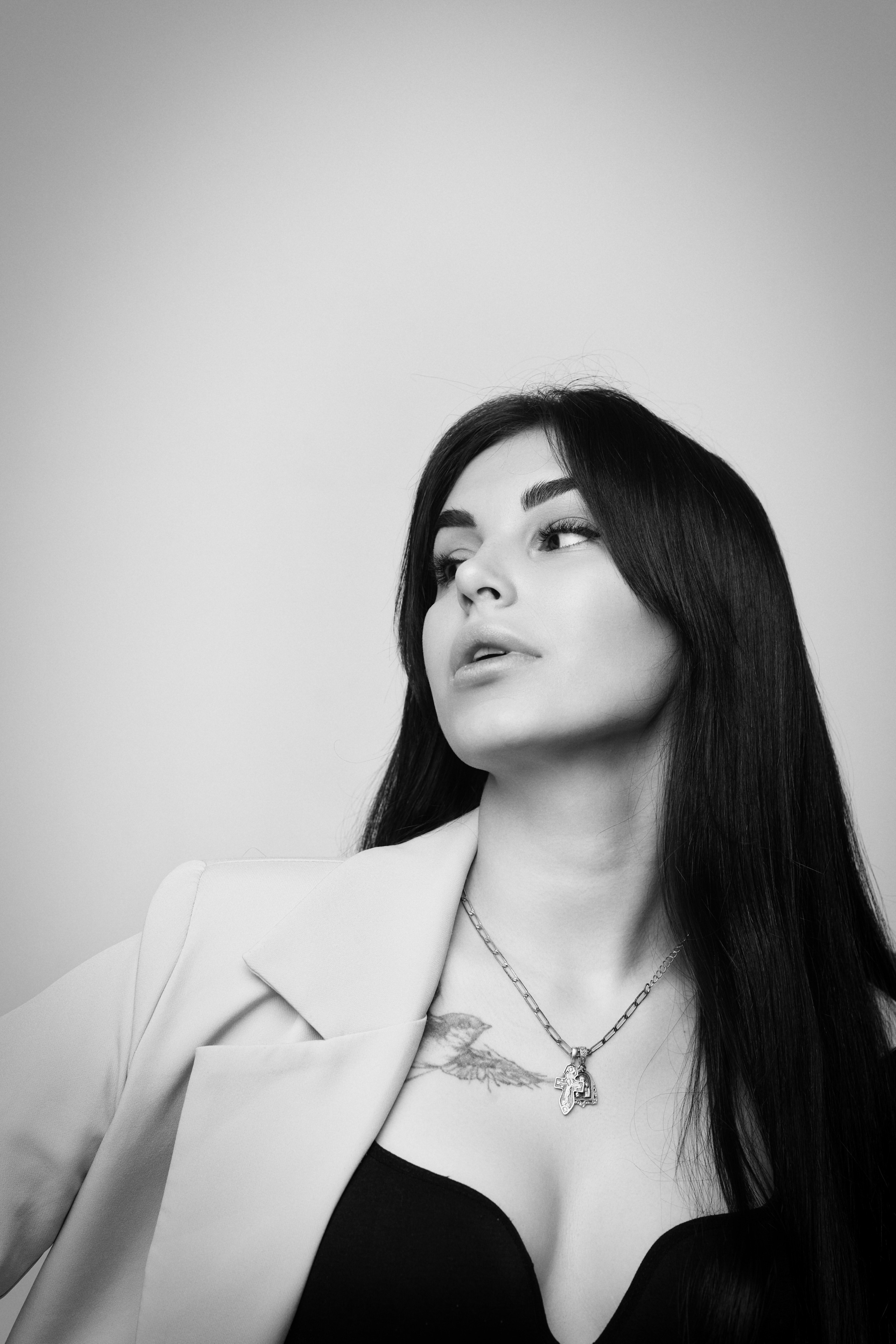 В платье на светлом фоне студии темноволосая модель Карина выглядит женственной и привлекательной.