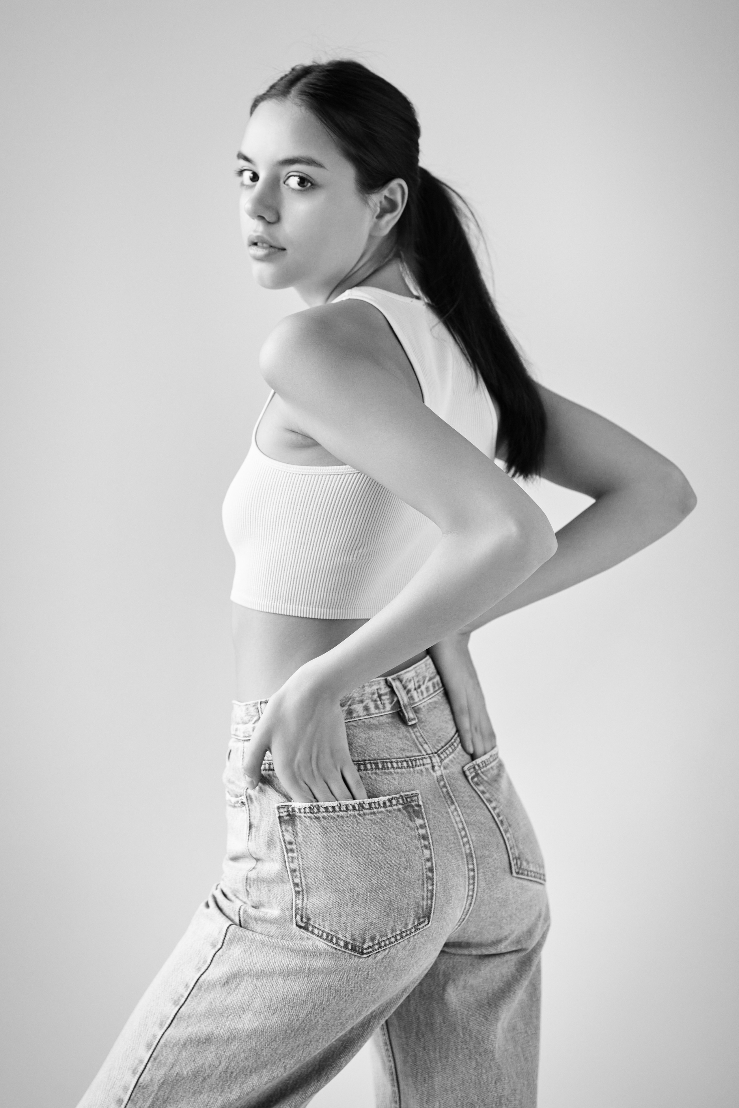 В студии на светлом фоне темноволосая красотка Амина в рубашке и кожаной юбке.