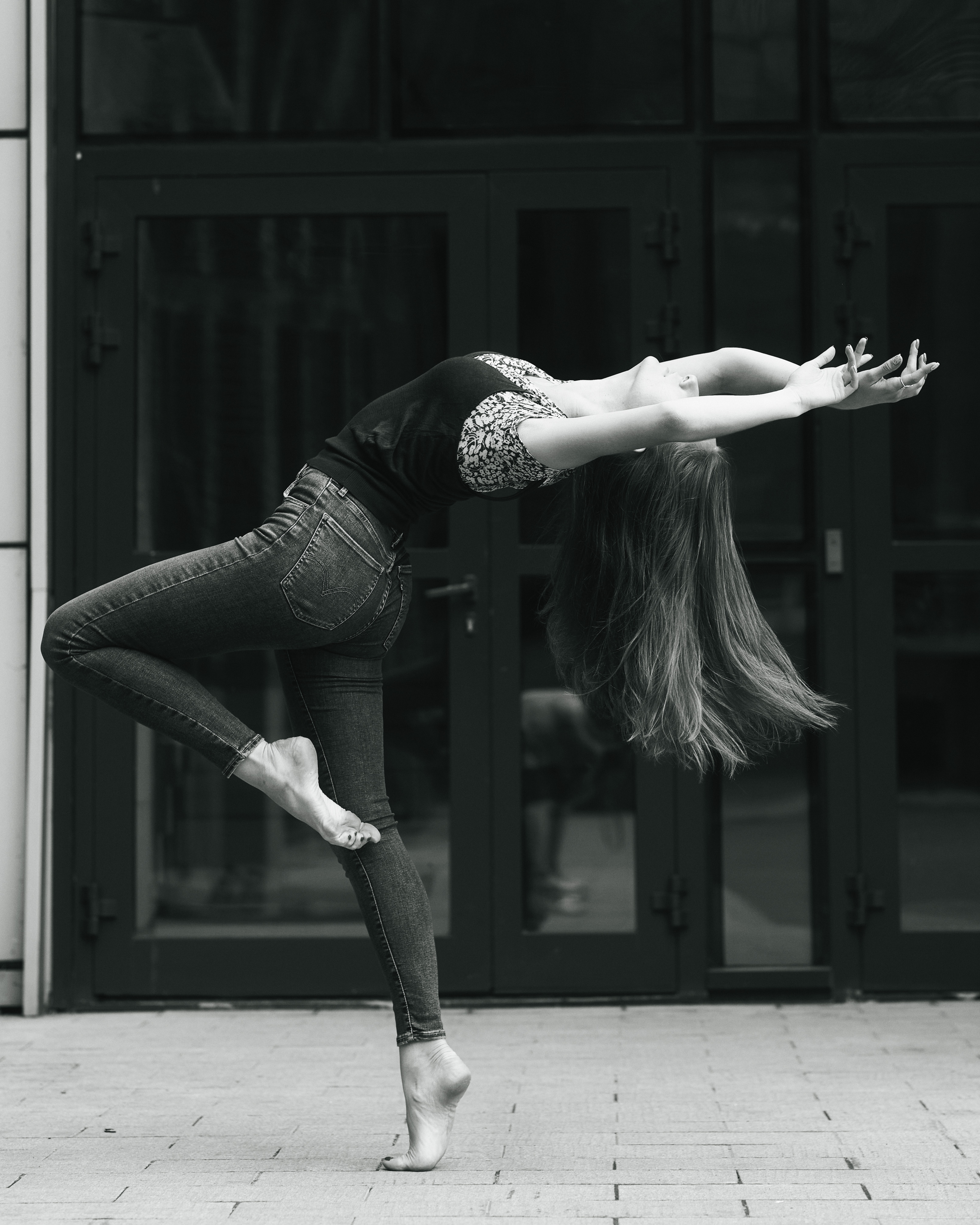 Темноволосая красавица Любовь на фоне городских зданий в платье или джинсах.