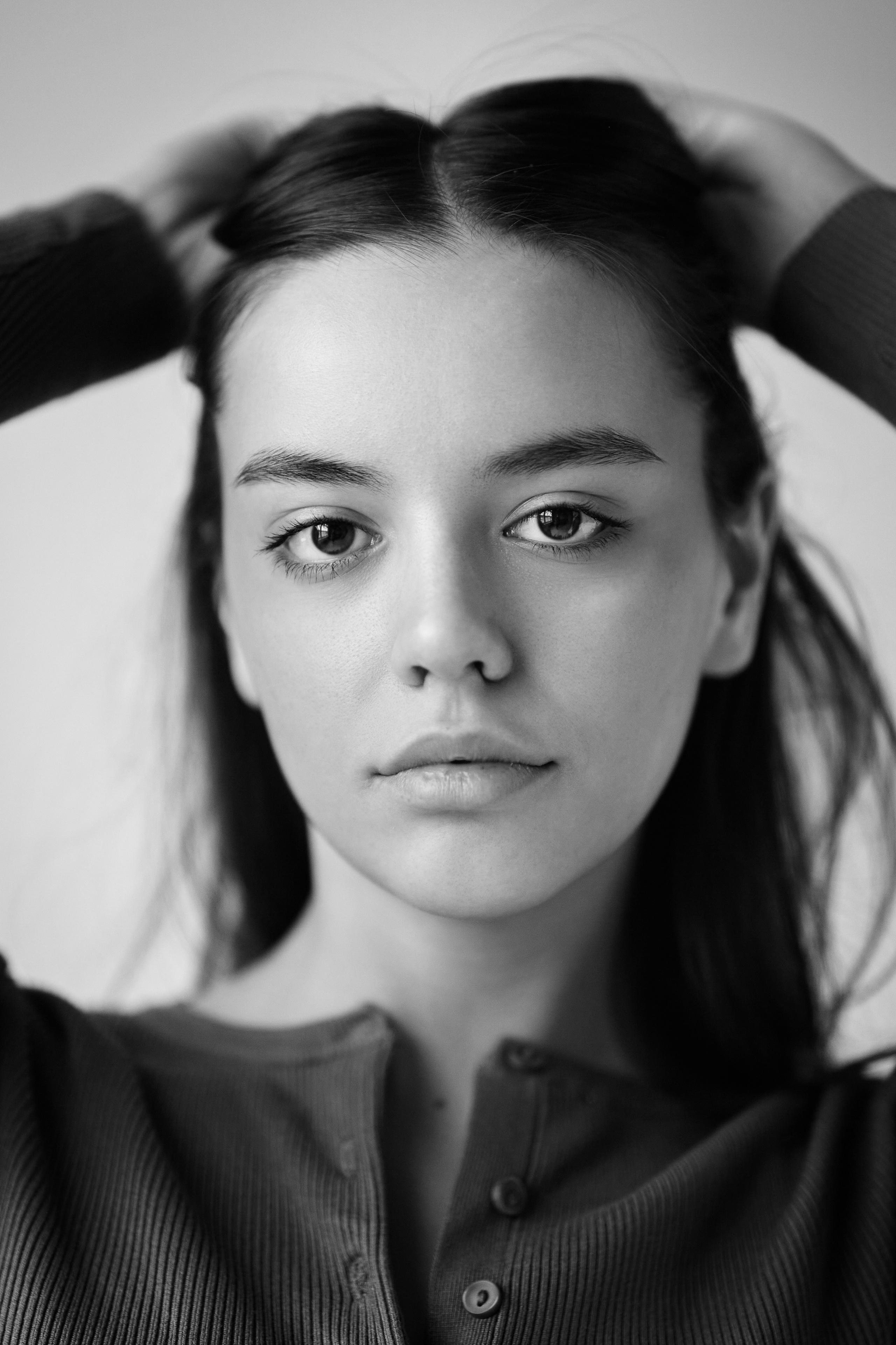 Темноволосая Амина на светлом фоне в рубашке в студии красиво позирует