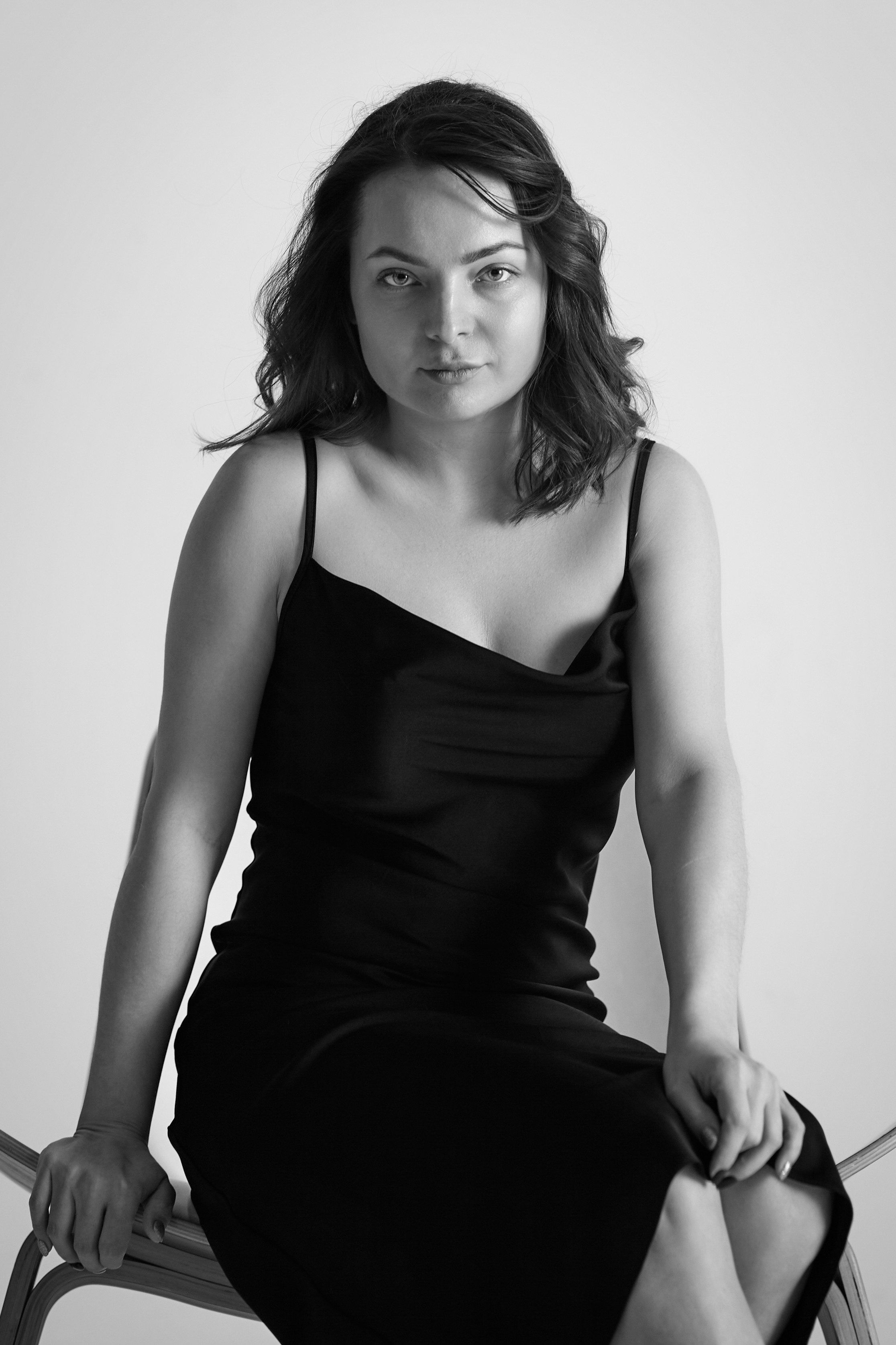 На стуле сидит модель Татьяна в топике в студии на светлом фоне.