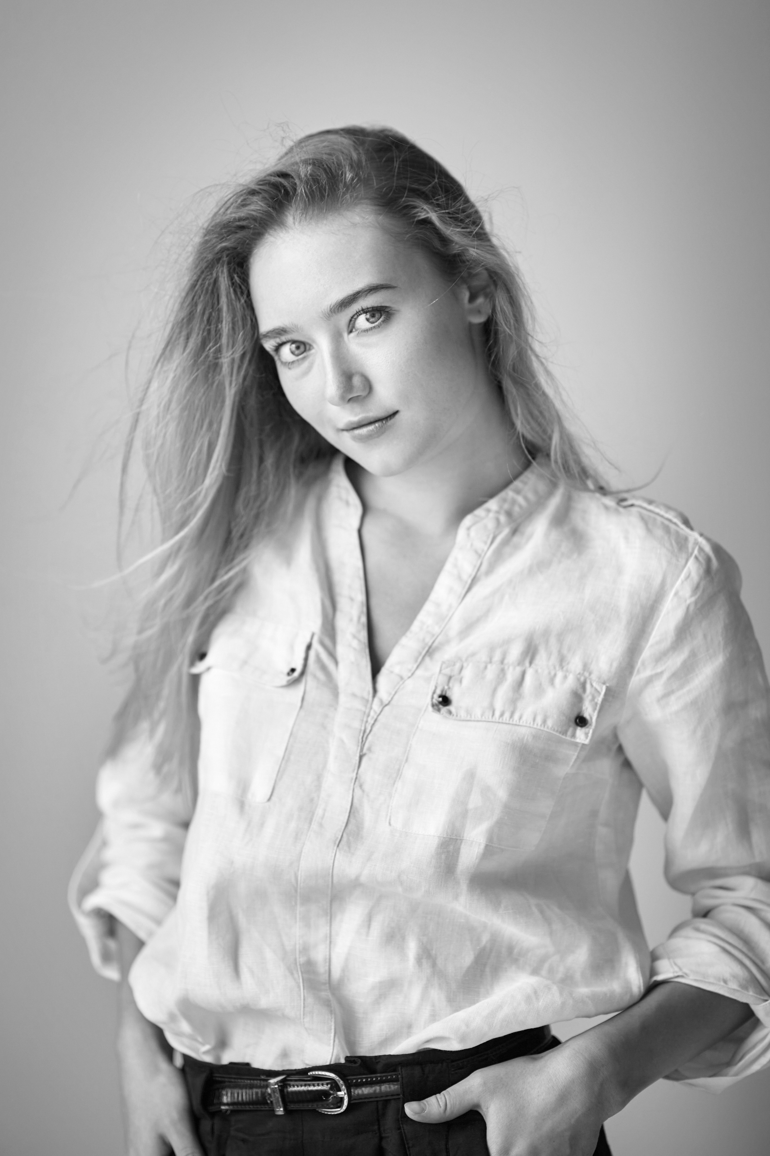 Светловолосая модель Алиса, одетая в своё платье, позирует на светлом фоне студии.