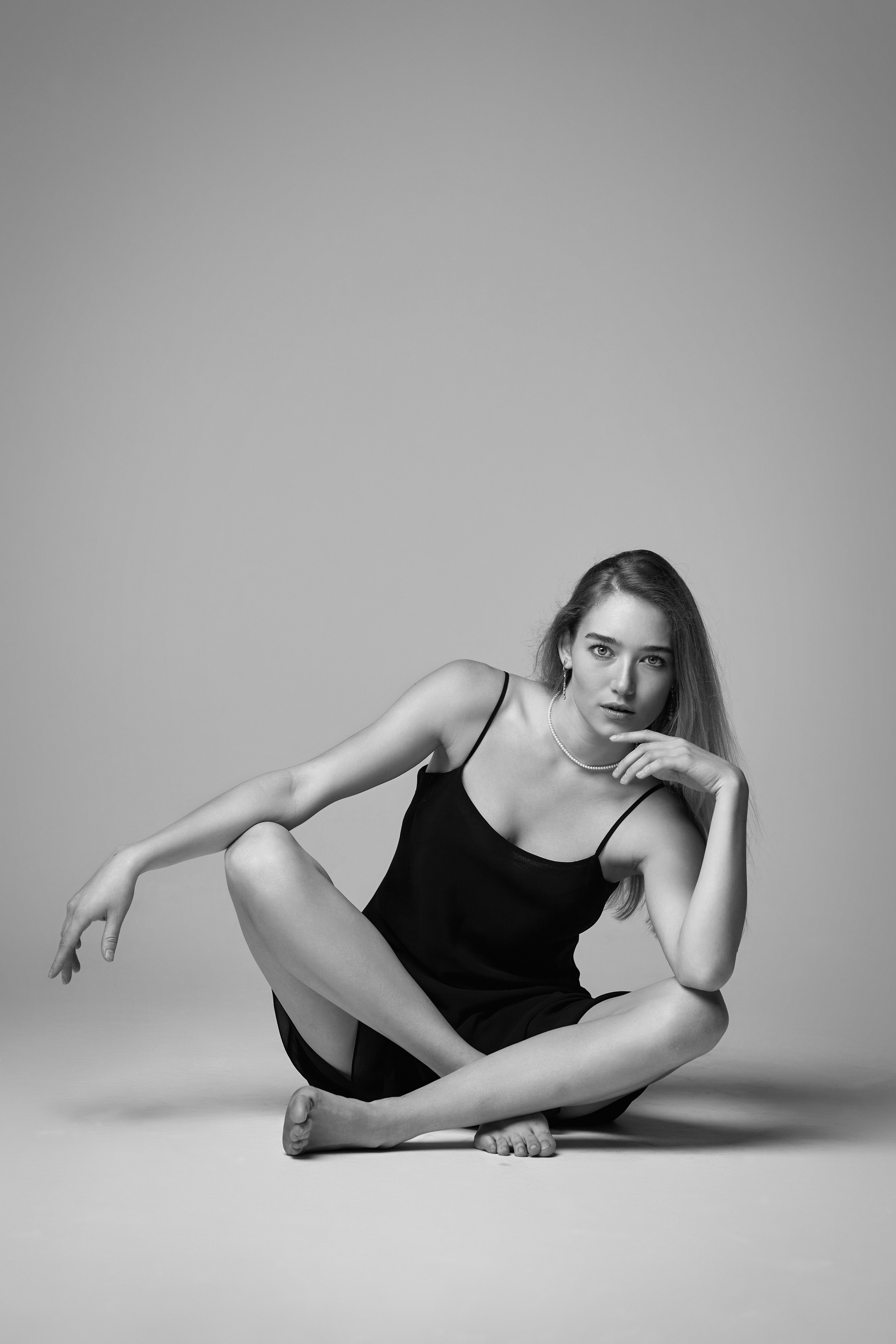 Фото светловолосой модели Алисы в студии на светлом фоне в белой рубашке и черной юбке, дополненной белыми туфля