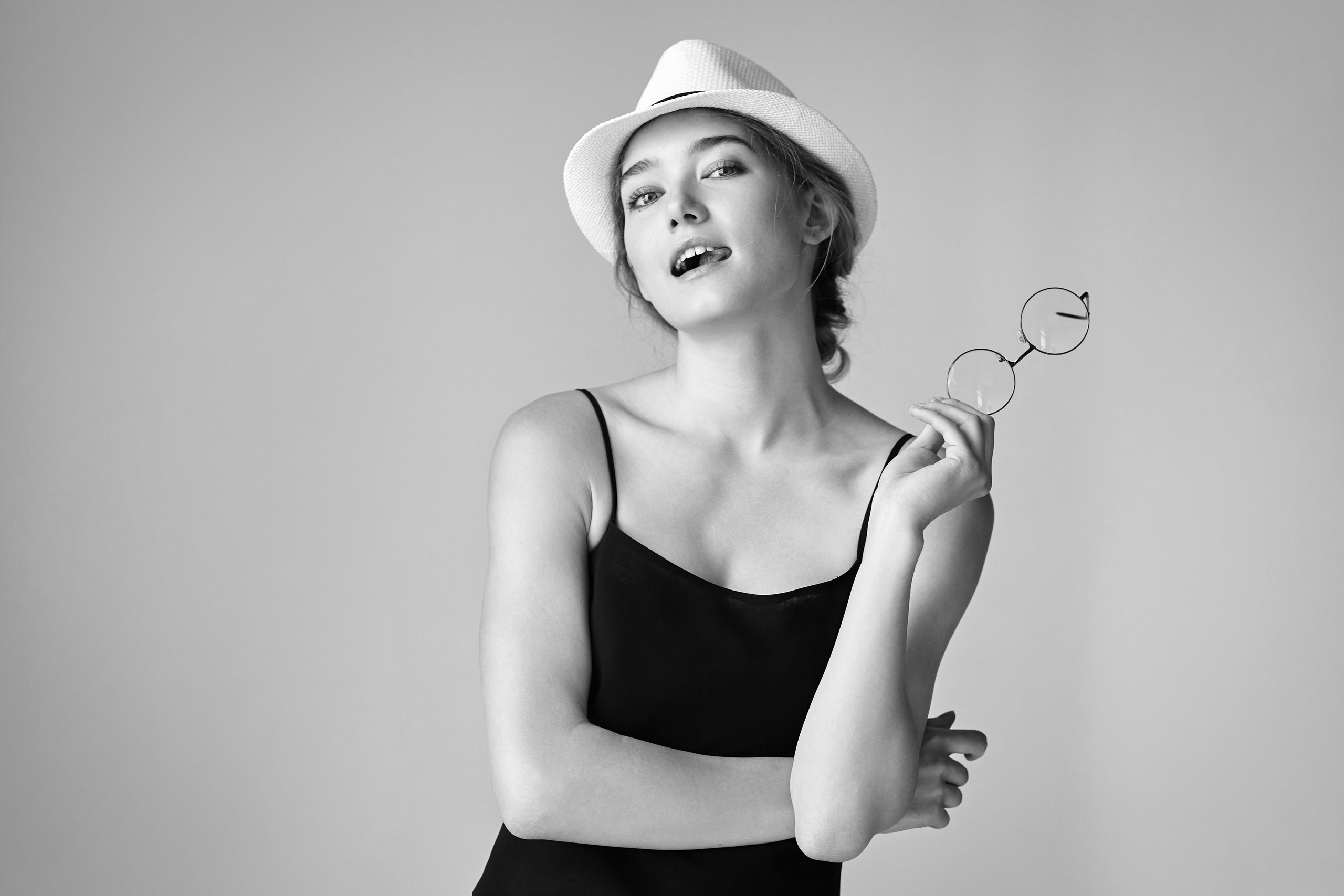 Светловолосая модель Алиса в студии на светлом фоне в белом платье с рюшами, создающее нежный образ.