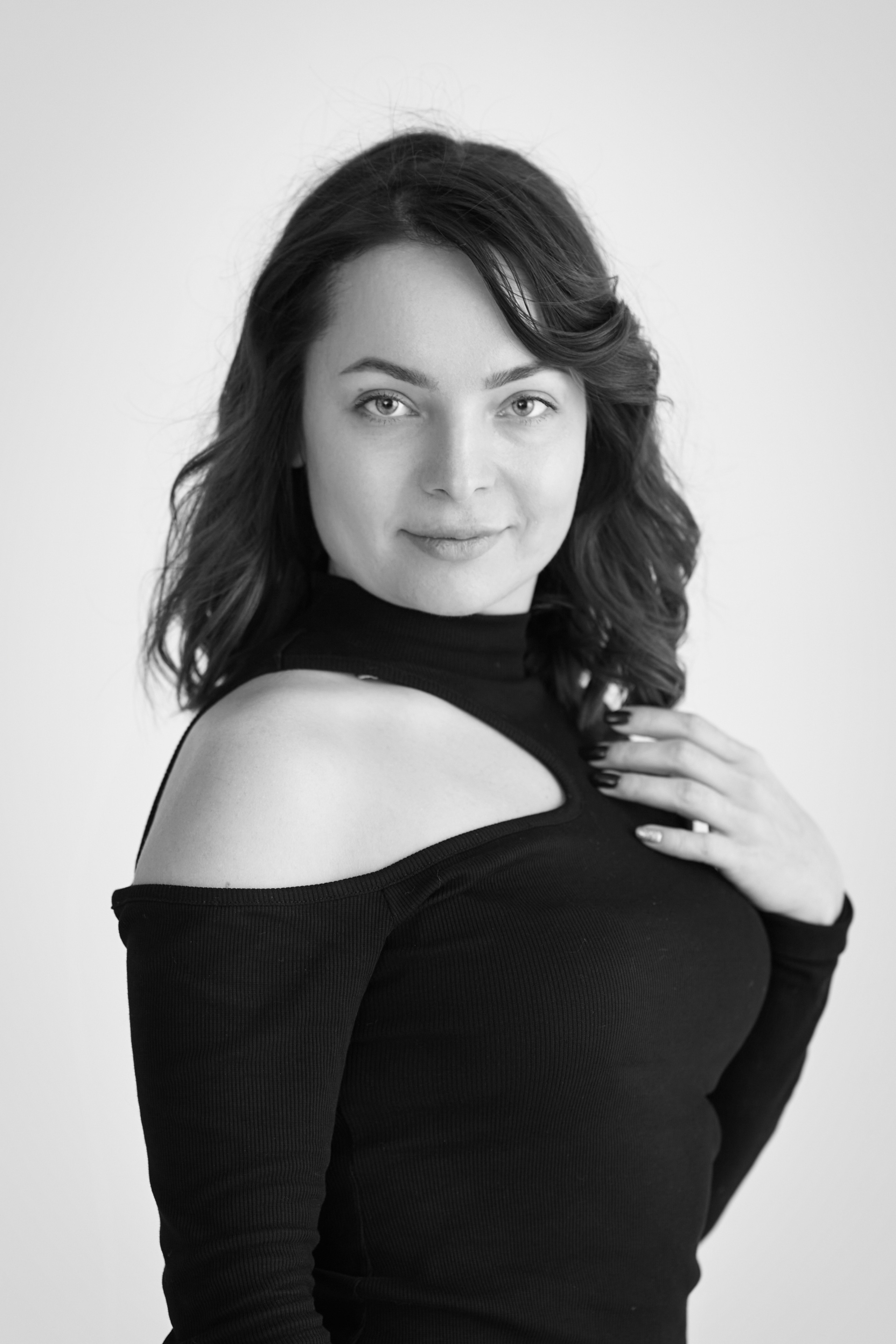 В студии на светлом фоне стоит темноволосая модель Татьяна, одетая в рубашку.