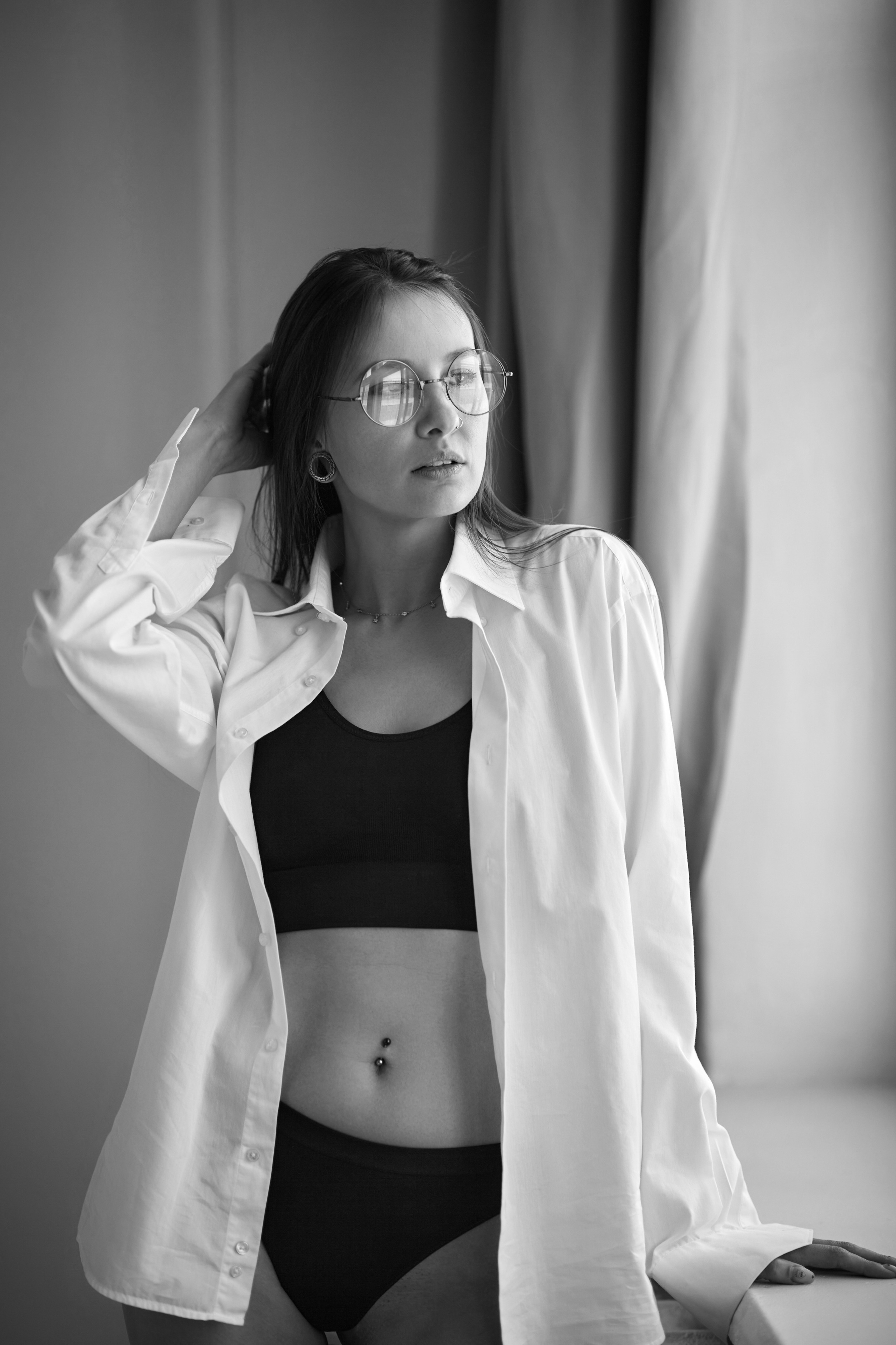 Девушка с темными волосами на фоне циклорамы в фотостудии смотрит прямо в камеру.