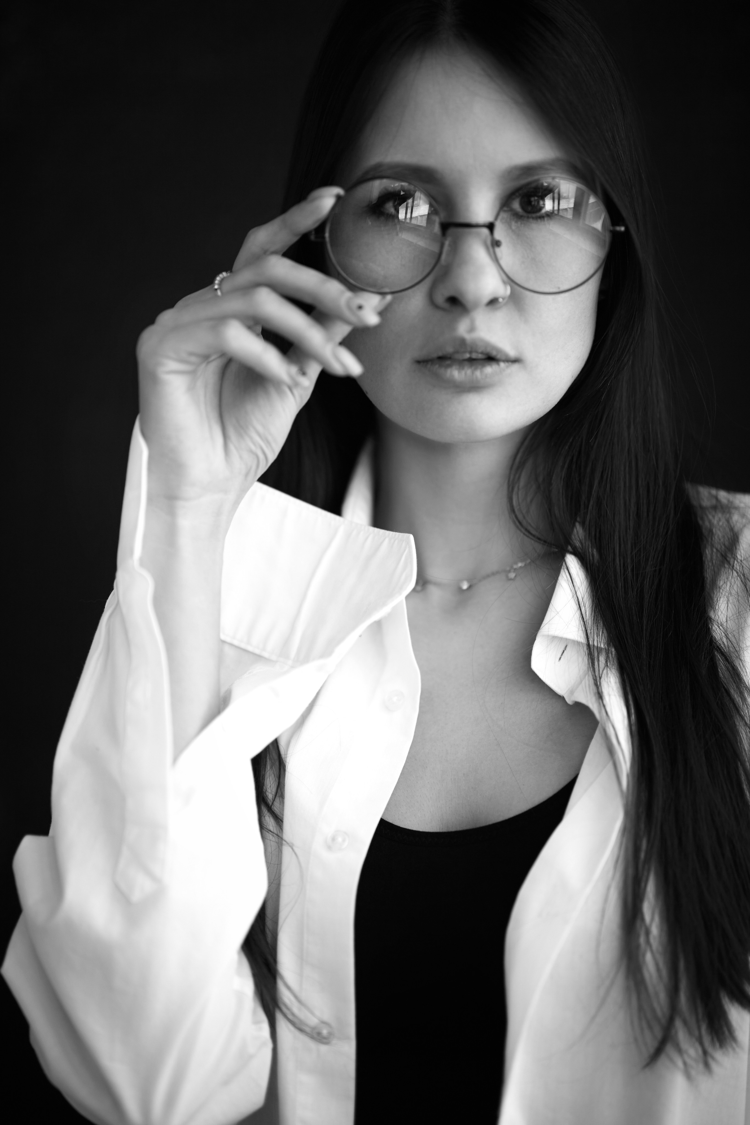 Темноволосая красавица на светлом фоне циклорамы в студии глядит в камеру.