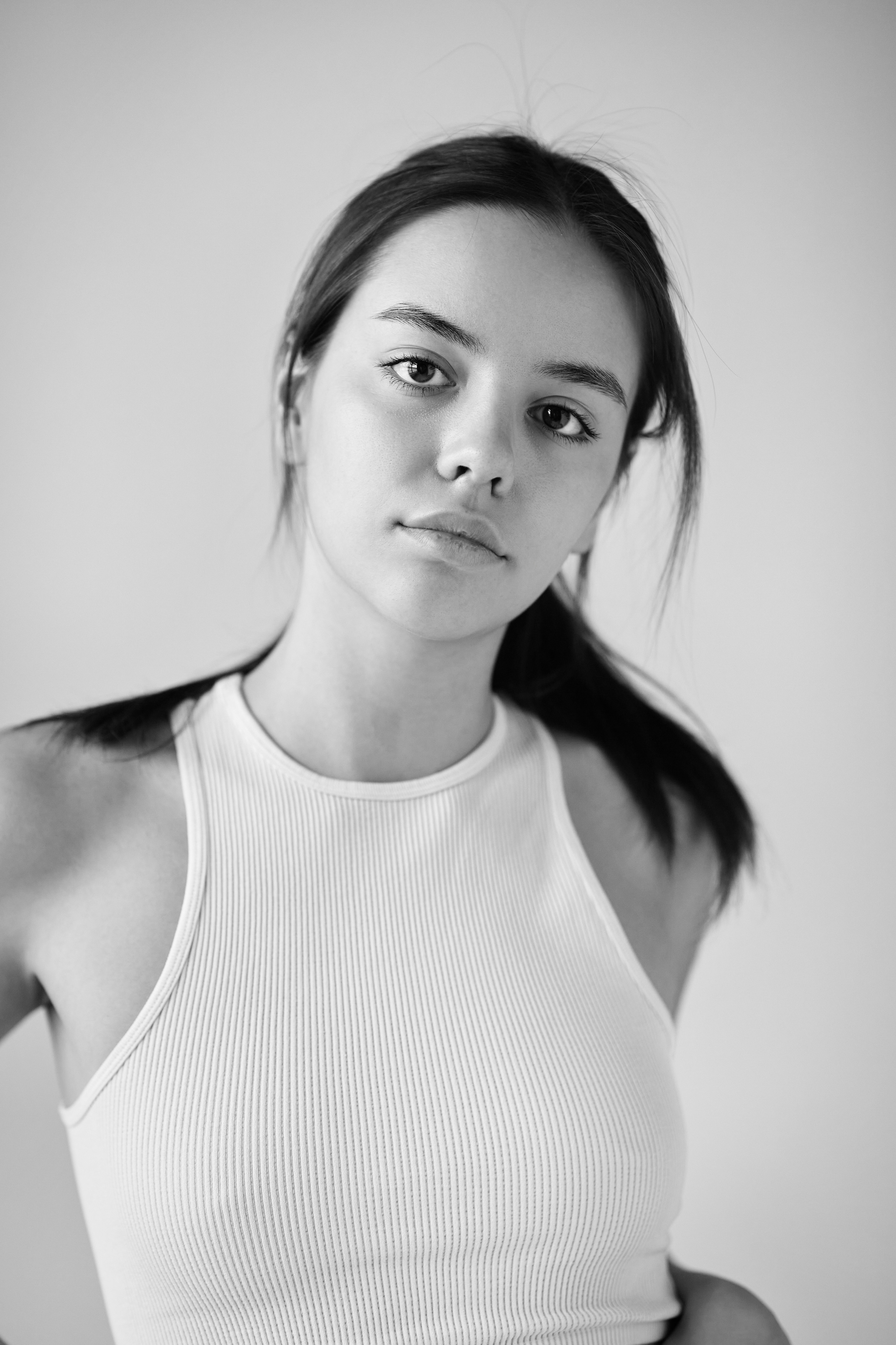 В студии на светлом фоне темноволосая модель Амина в светлом топике