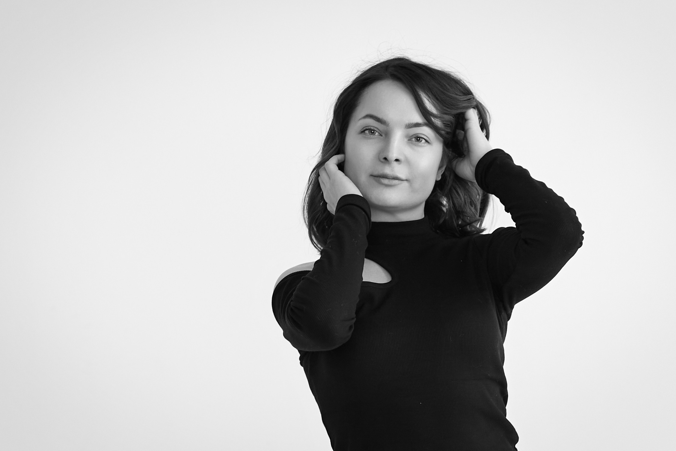 Темноволосая модель Татьяна сидит на стуле в светлой рубашке на фоне свет