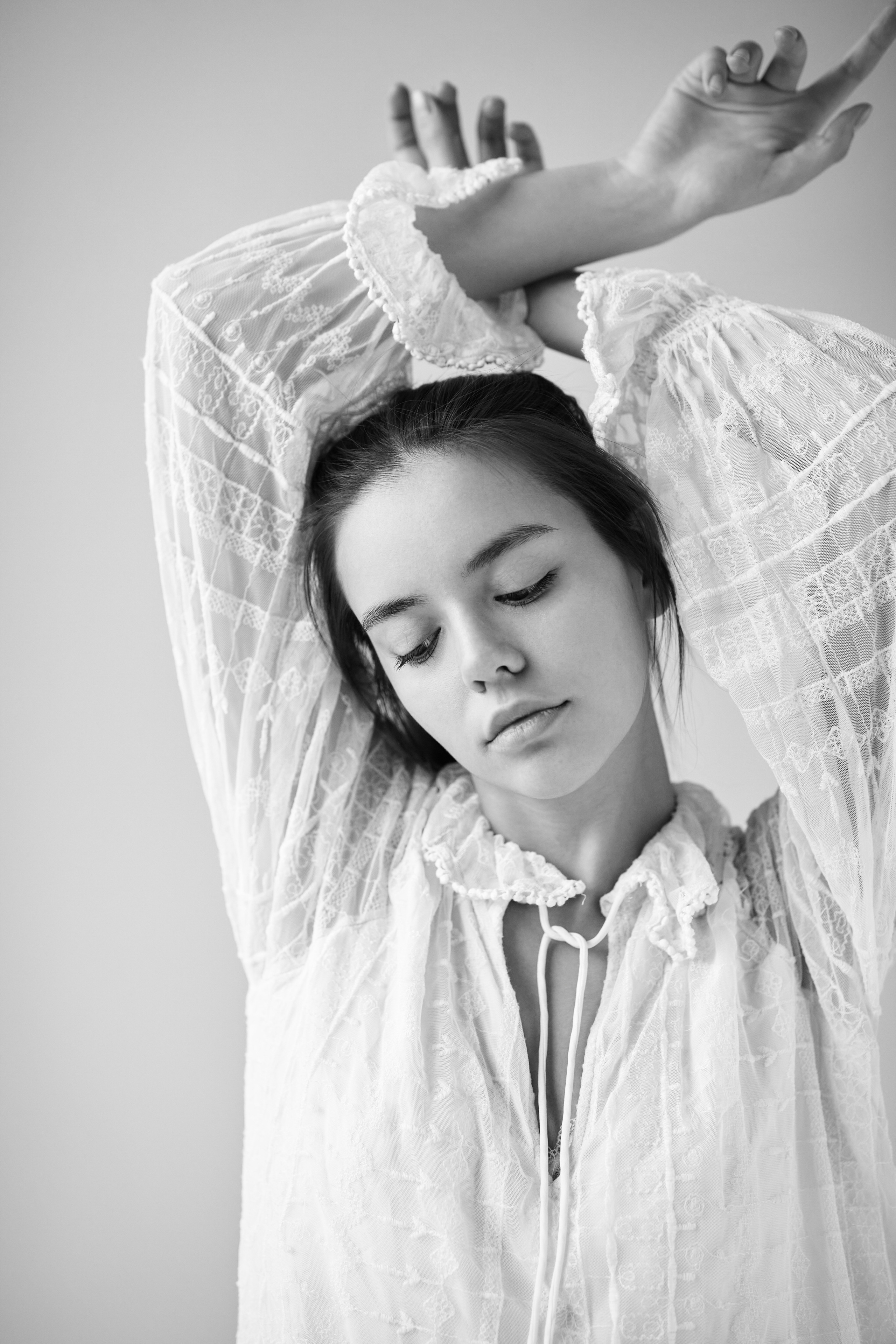 Модель Амина в светлых нарядах на фоне студии во время фотосессии.