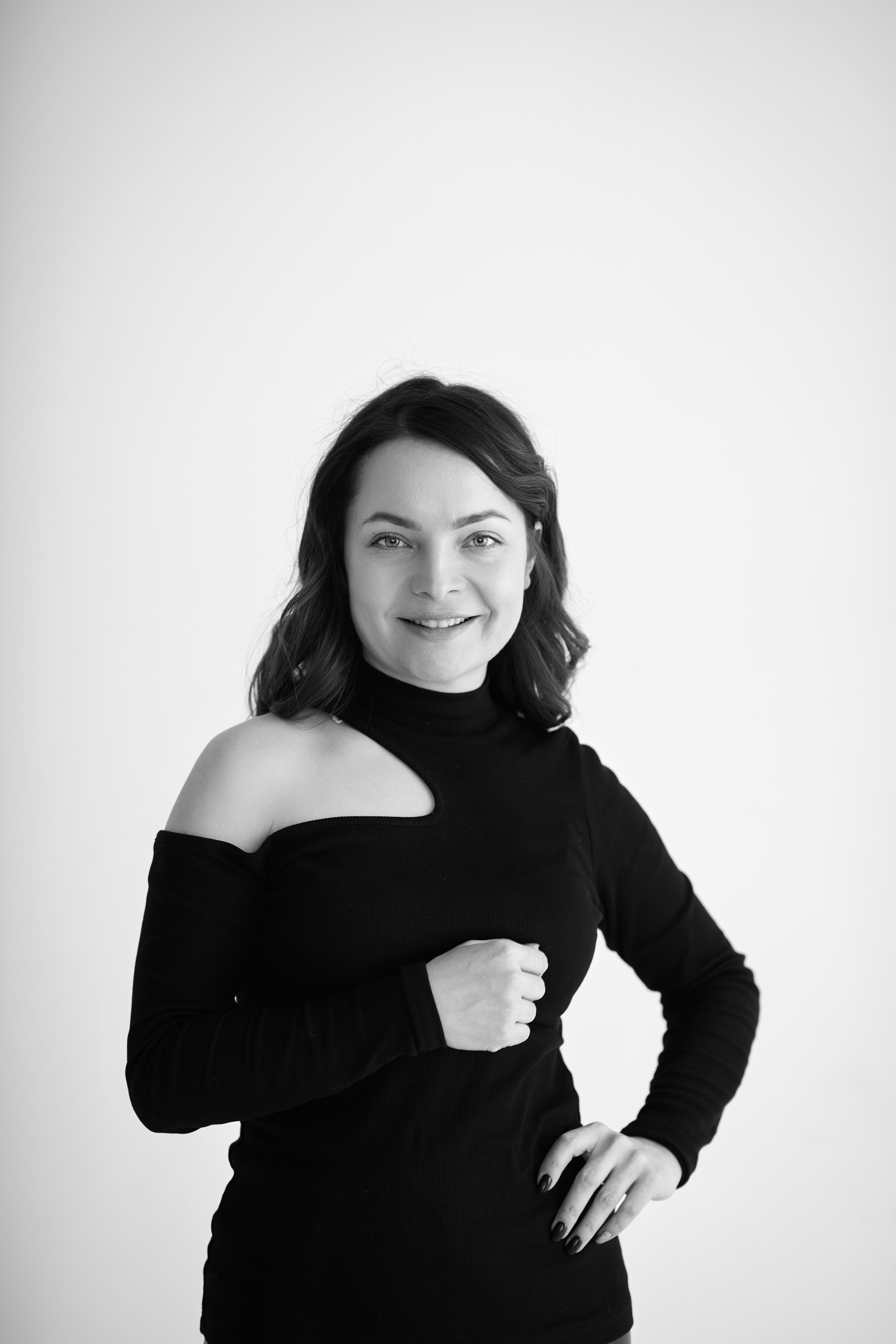 Темноволосая модель Татьяна находится на фоне светлого фона в светлом топике в студии.