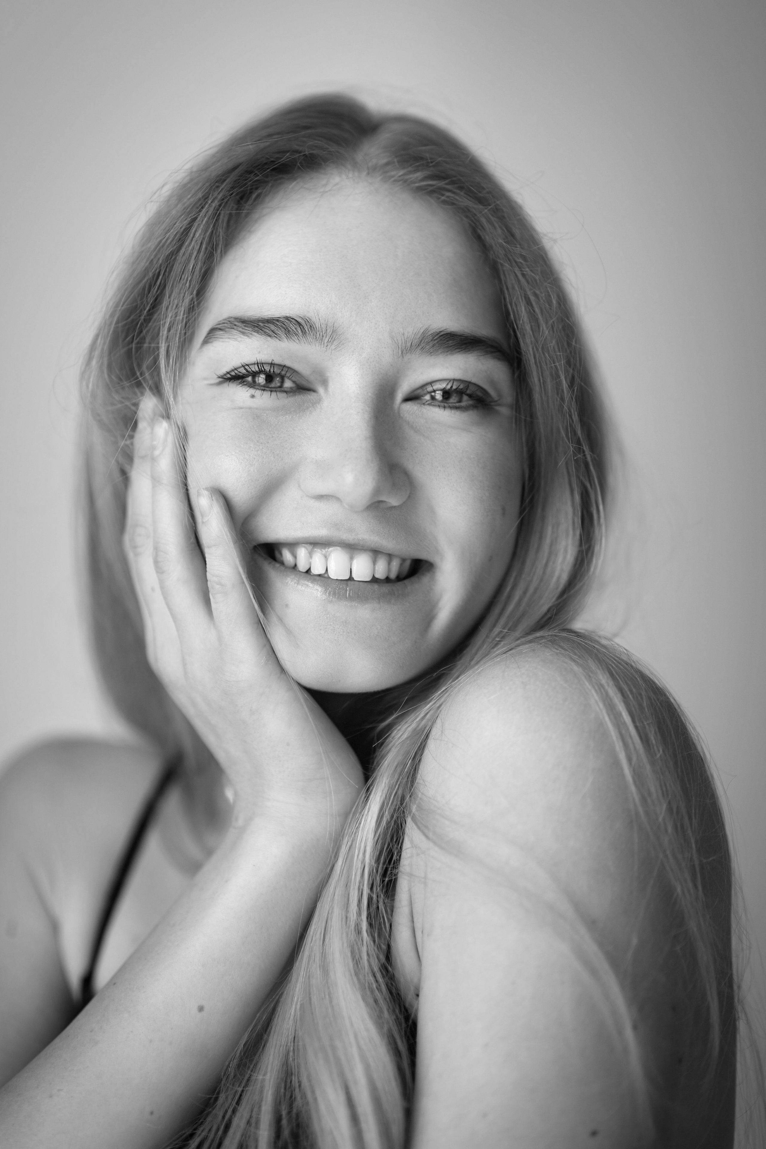 Светловолосая модель Алиса в студии на светлом фоне в черной рубашке и облегающих брюках.