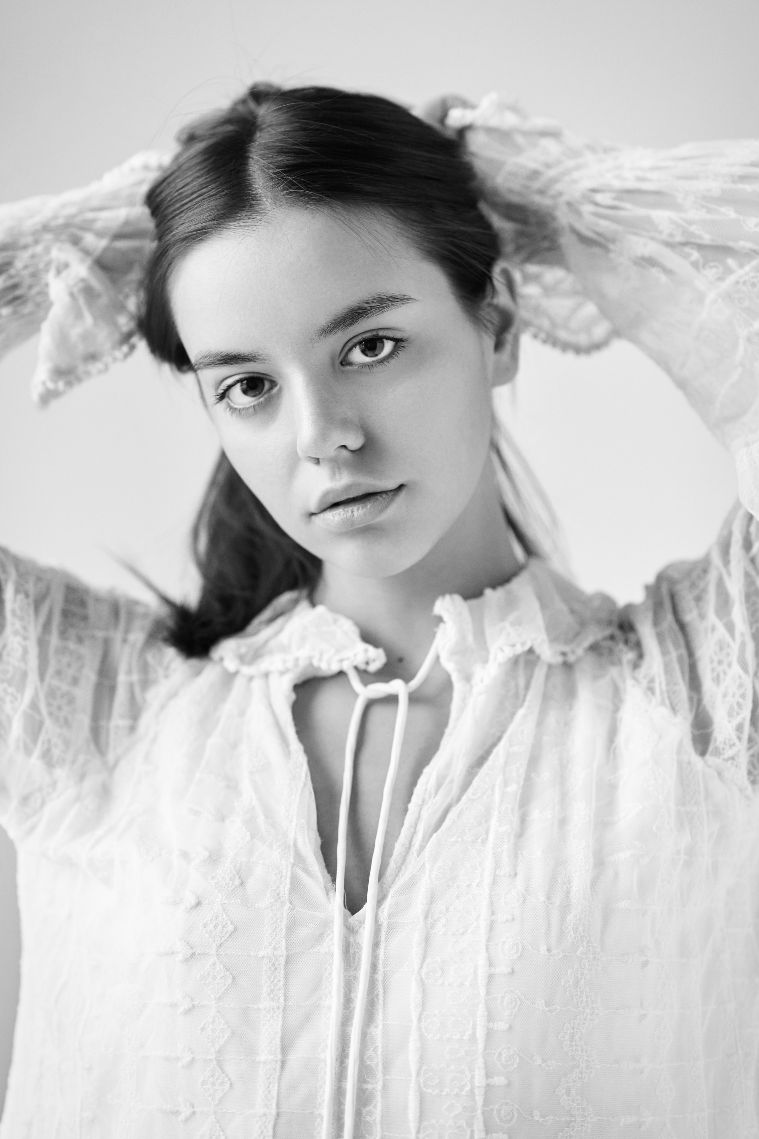 Темноволосая красотка Амина в светлом наряде на фоне студии.