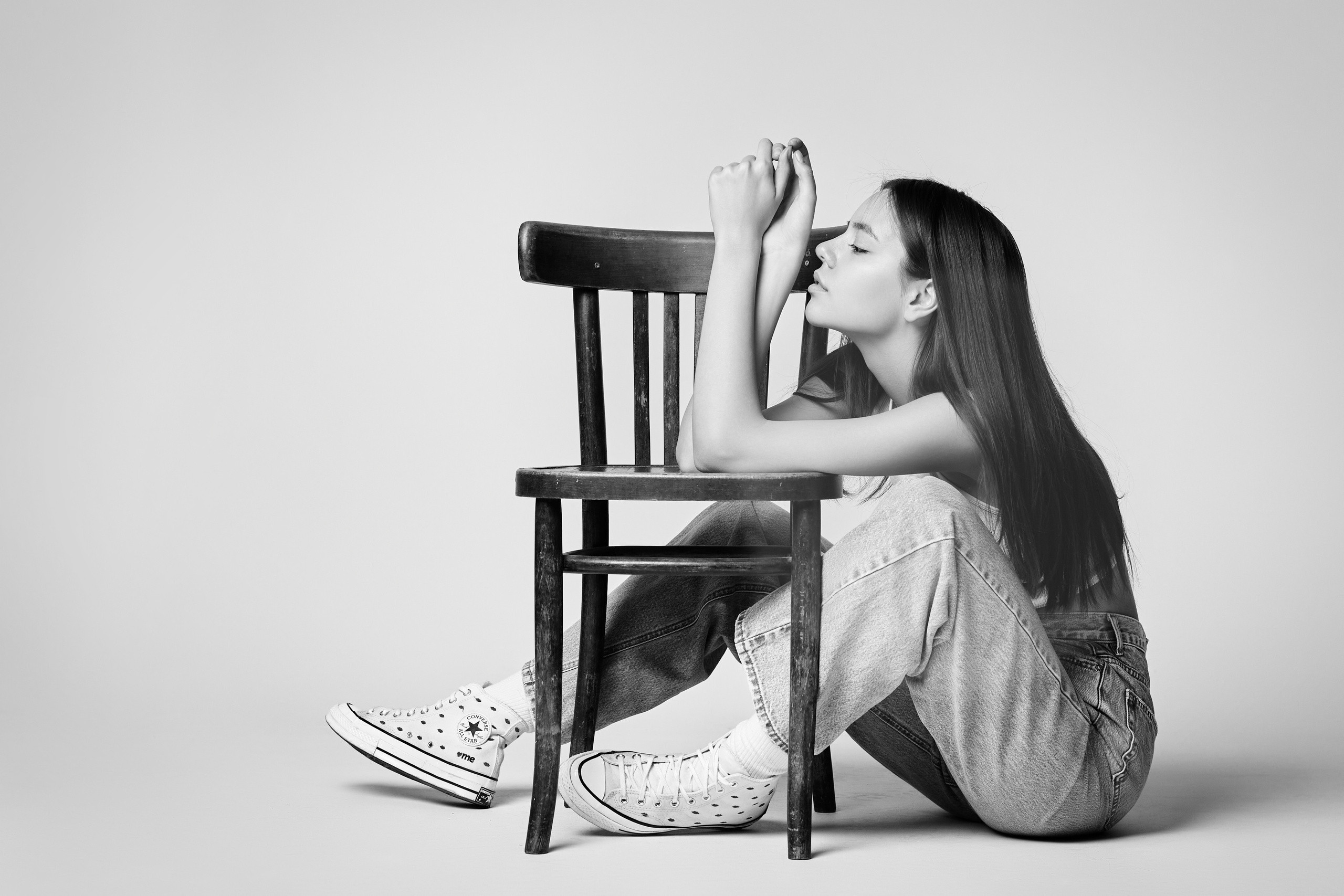 Модель Амина в темном топике стоит на светлом фоне в студии, ее волосы аккуратно зачесаны.