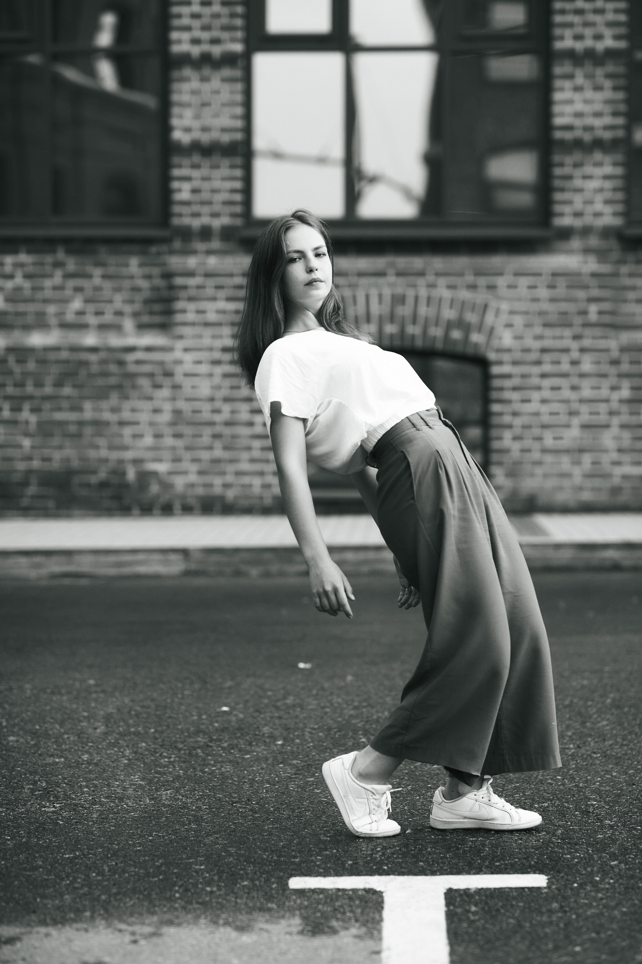 Темноволосая модель Дарья на улице города в светлой кофте и широких брюках.