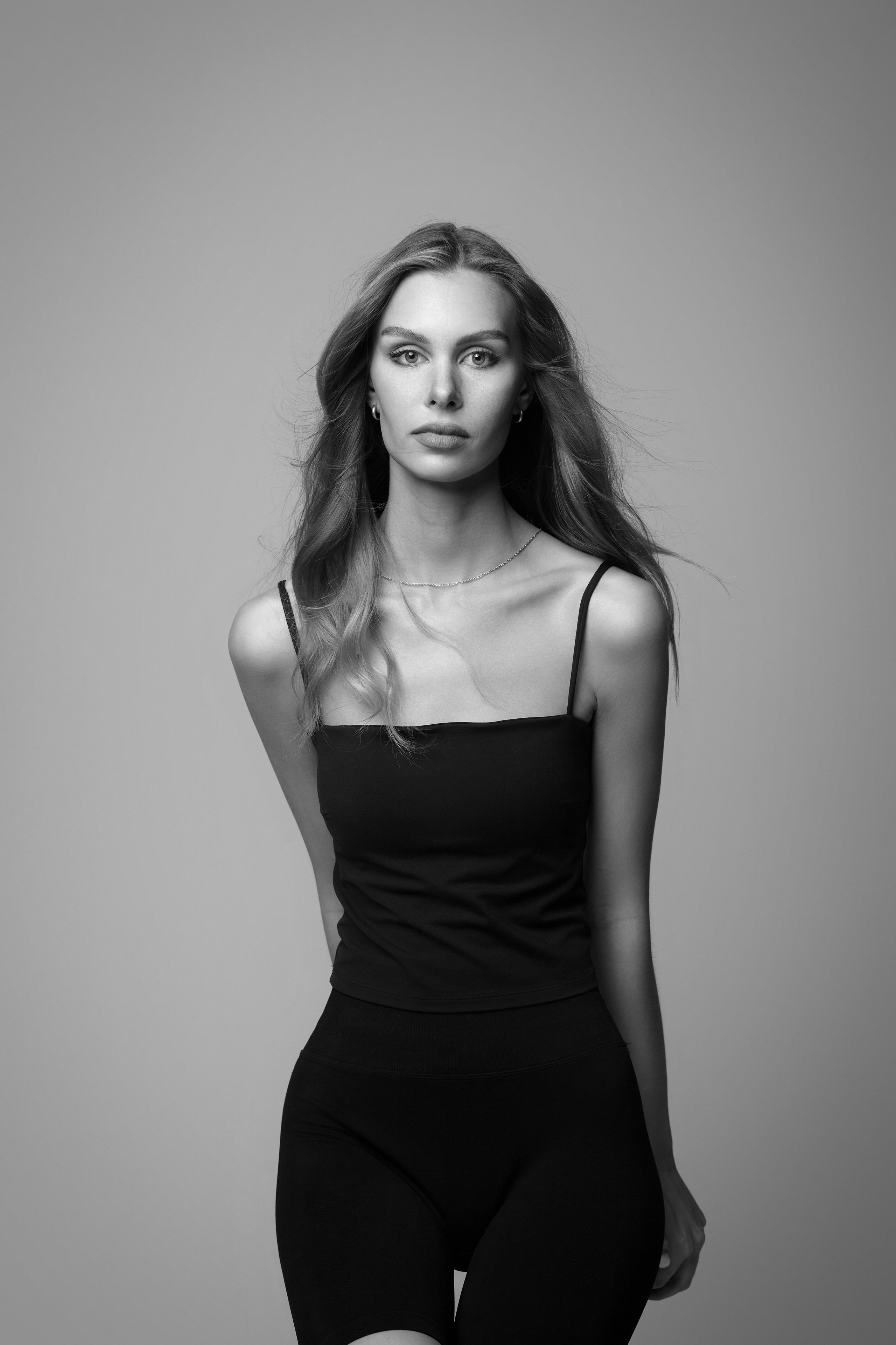 Шляпа и очки делают образ темноволосой девушки на светлом фоне более утончённым и изысканным