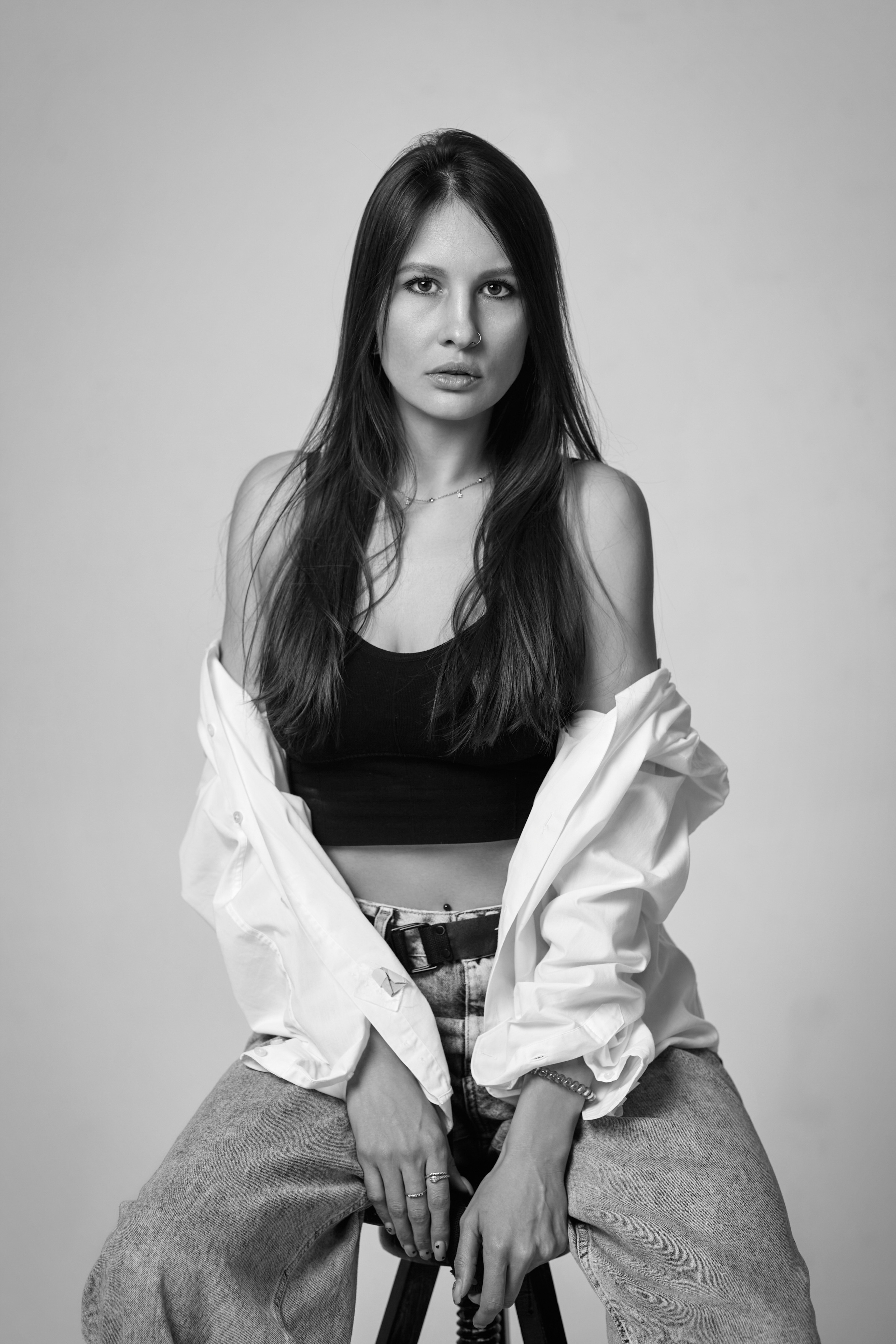 Девушка с темными волосами на циклорамном фоне.