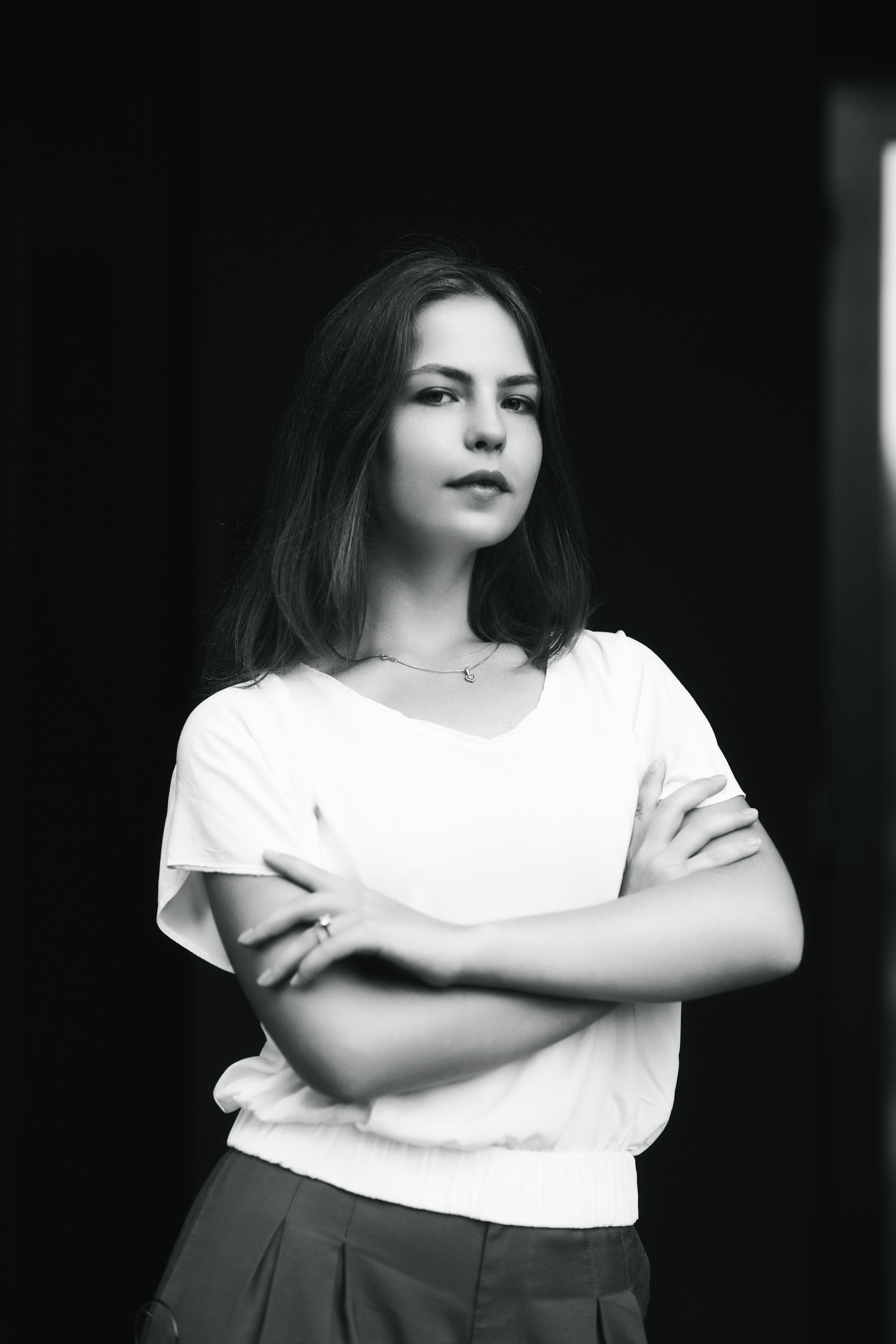 Дарья, модель с темными волосами, позирует на улице Москвы в светлой кофте и широких брюках.