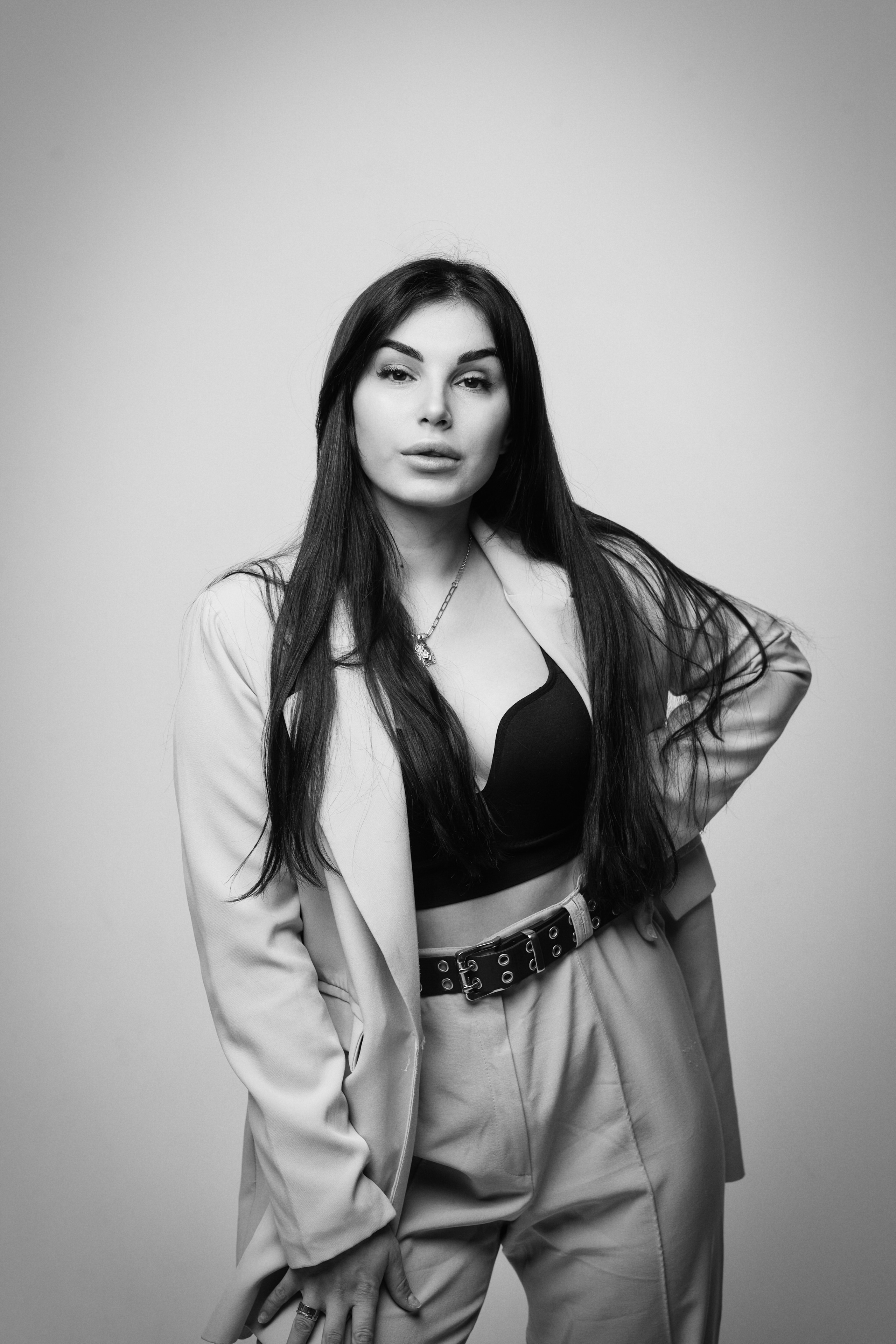 Темноволосая Карина в рубашке на светлом фоне студии