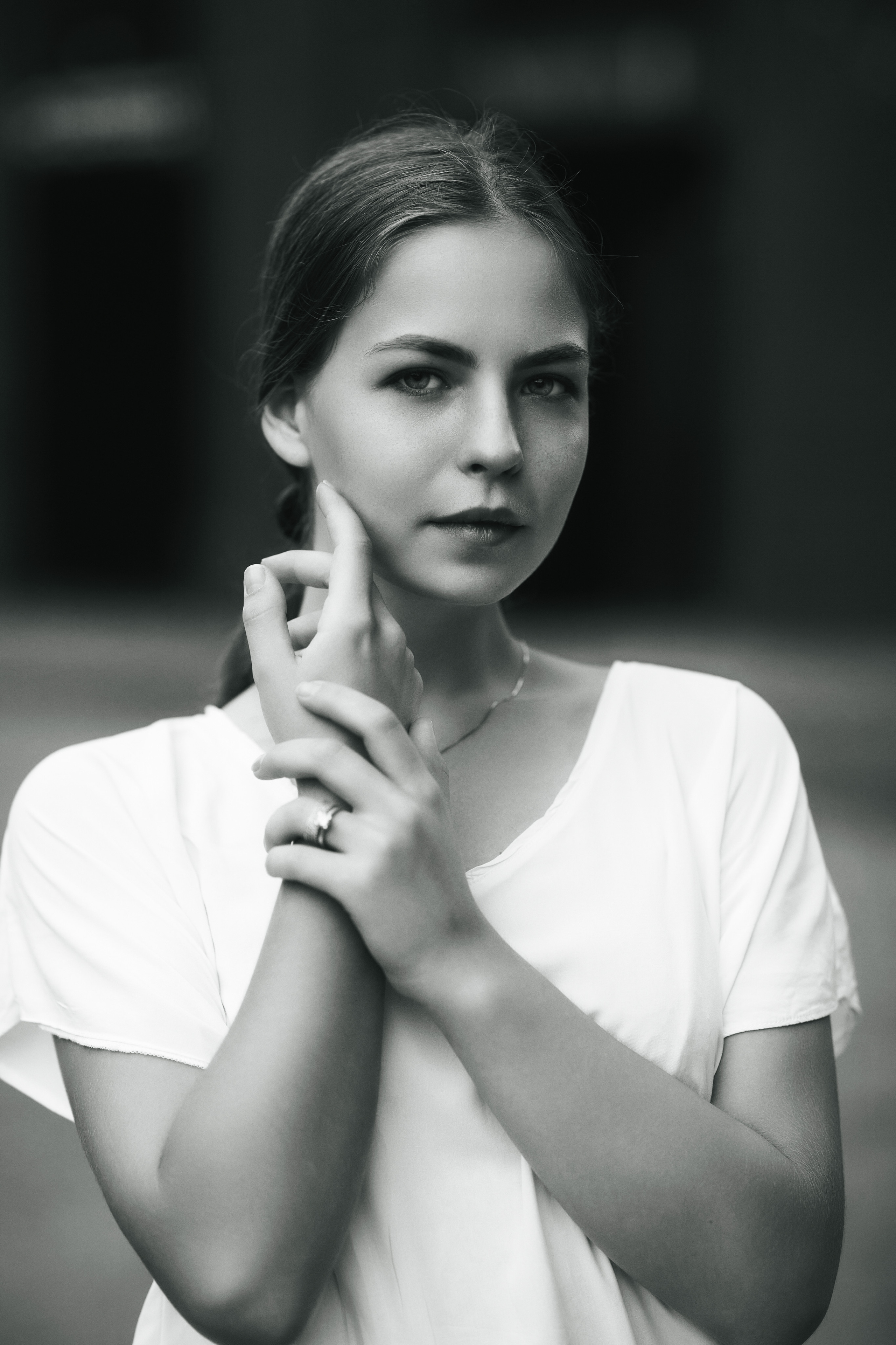 Дарья на фоне городского пейзажа в светлой кофте и с темными волосами