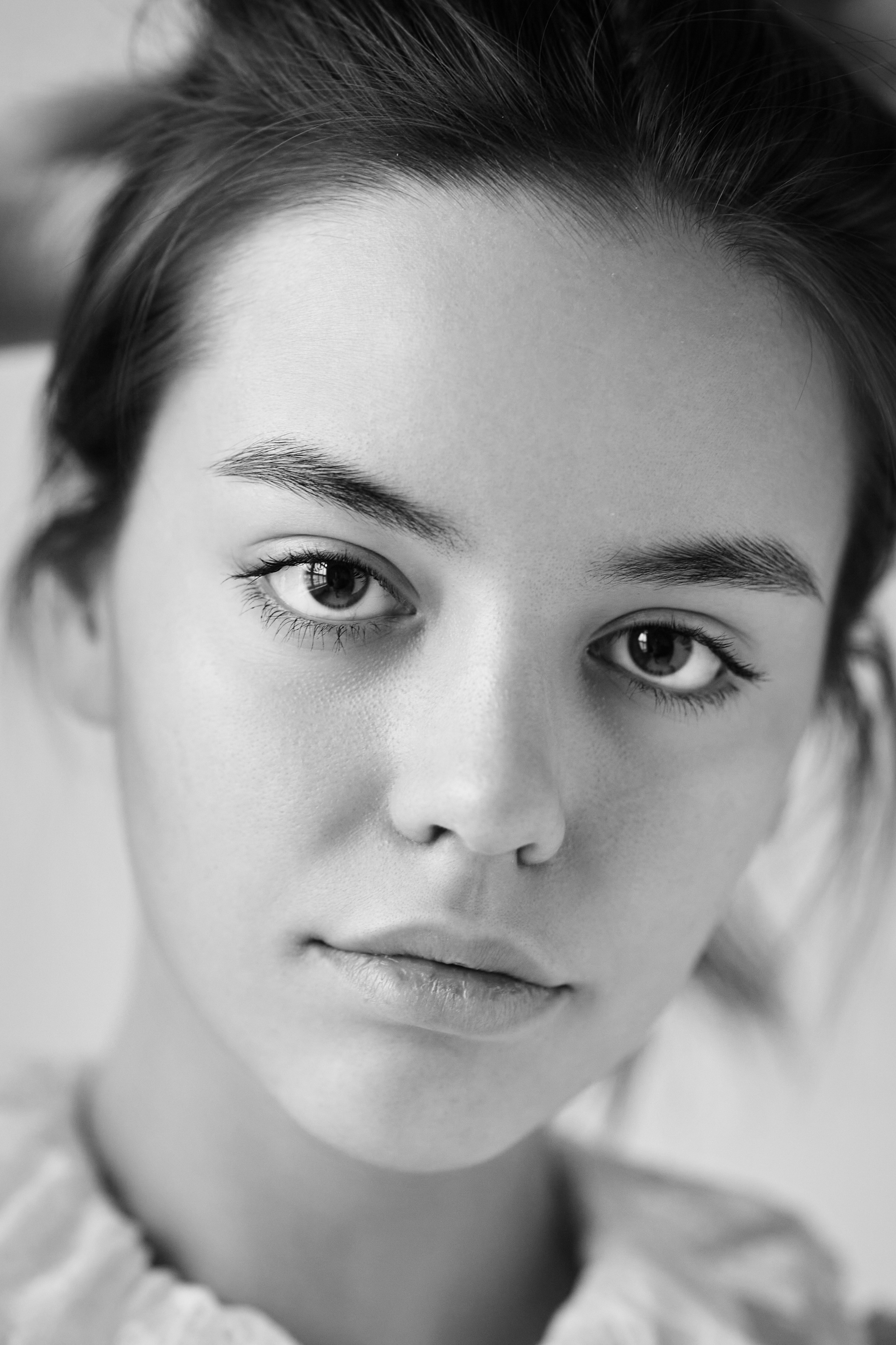 Сексуальная темноволосая модель Амина на светлом фоне в облегающем светлом платье с открытой спиной.