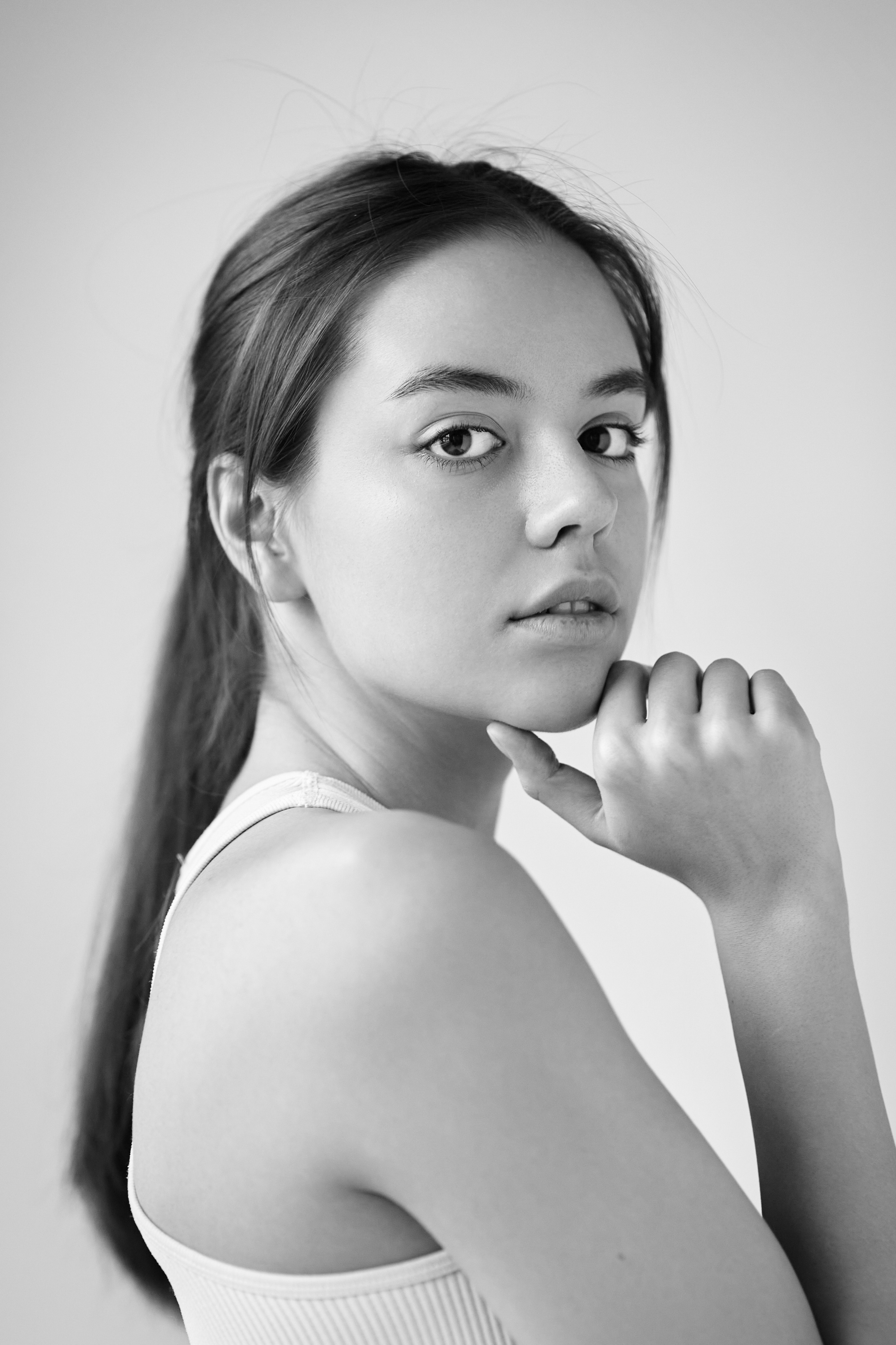 Модель Амина в студии на светлом фоне одета в рубашку, ее волосы небрежно завиты.