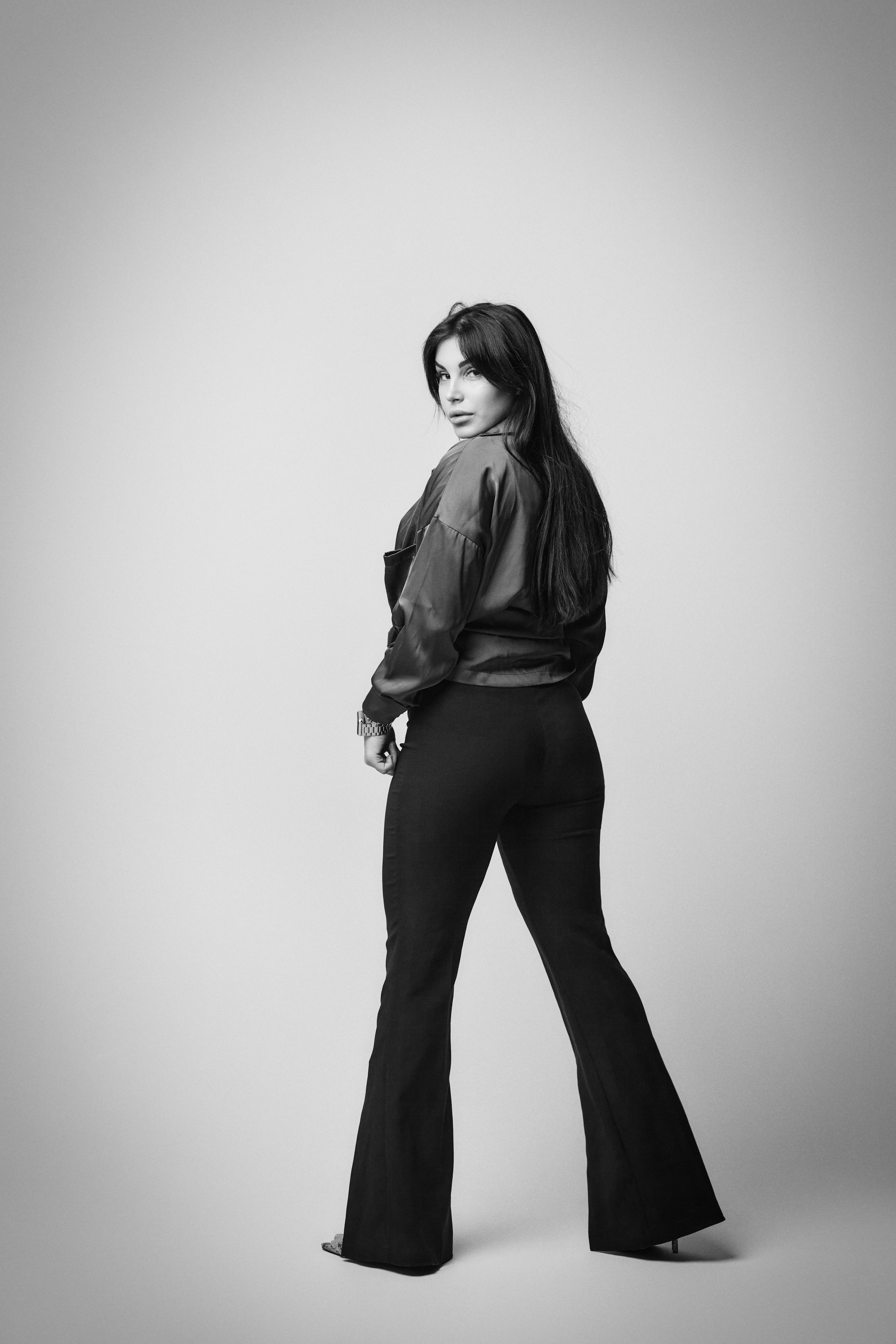 Темноволосая модель Карина в рубашке на светлом фоне студии, простой и элегантный образ