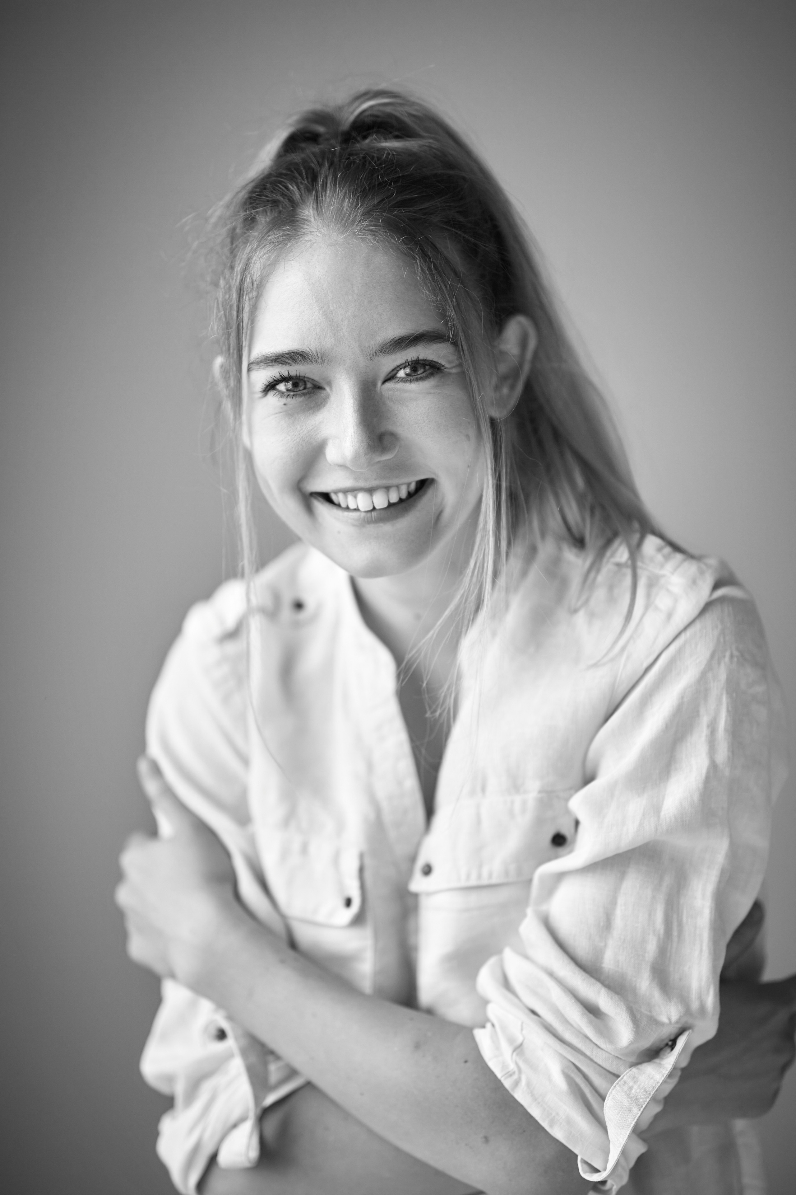 Алиса, модель с идеальными пропорциями, предстаёт перед камерой в студии на светлом фоне, одетая в платье или рубашку.