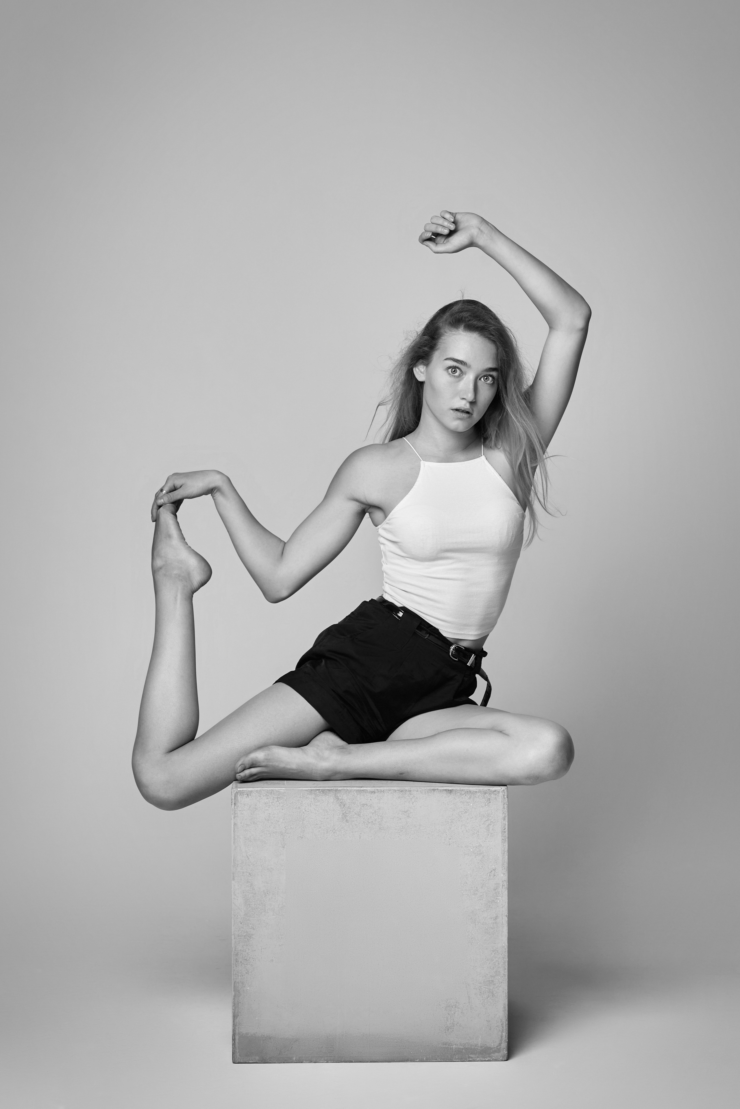 Светловолосая Алиса, позируя на светлом фоне студии, привлекает внимание в своём нежном платье.