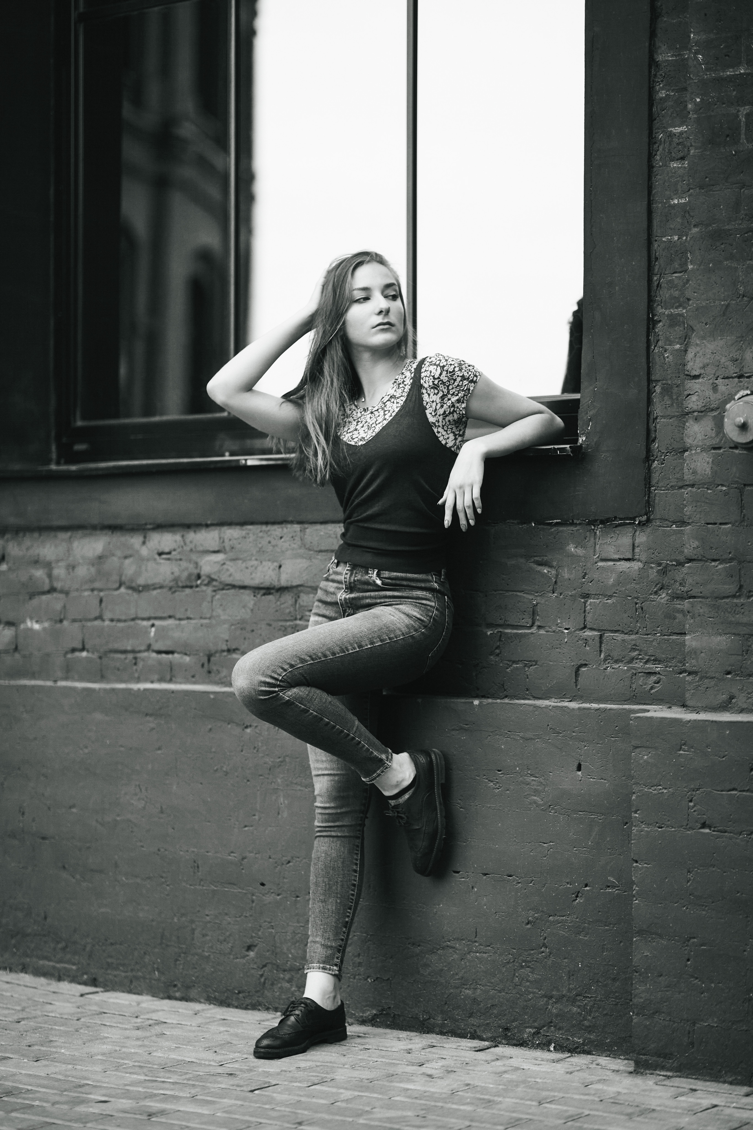 Модель Любовь, темноволосая и изысканная, на улице в городе в простом платье или стильных джинсах.