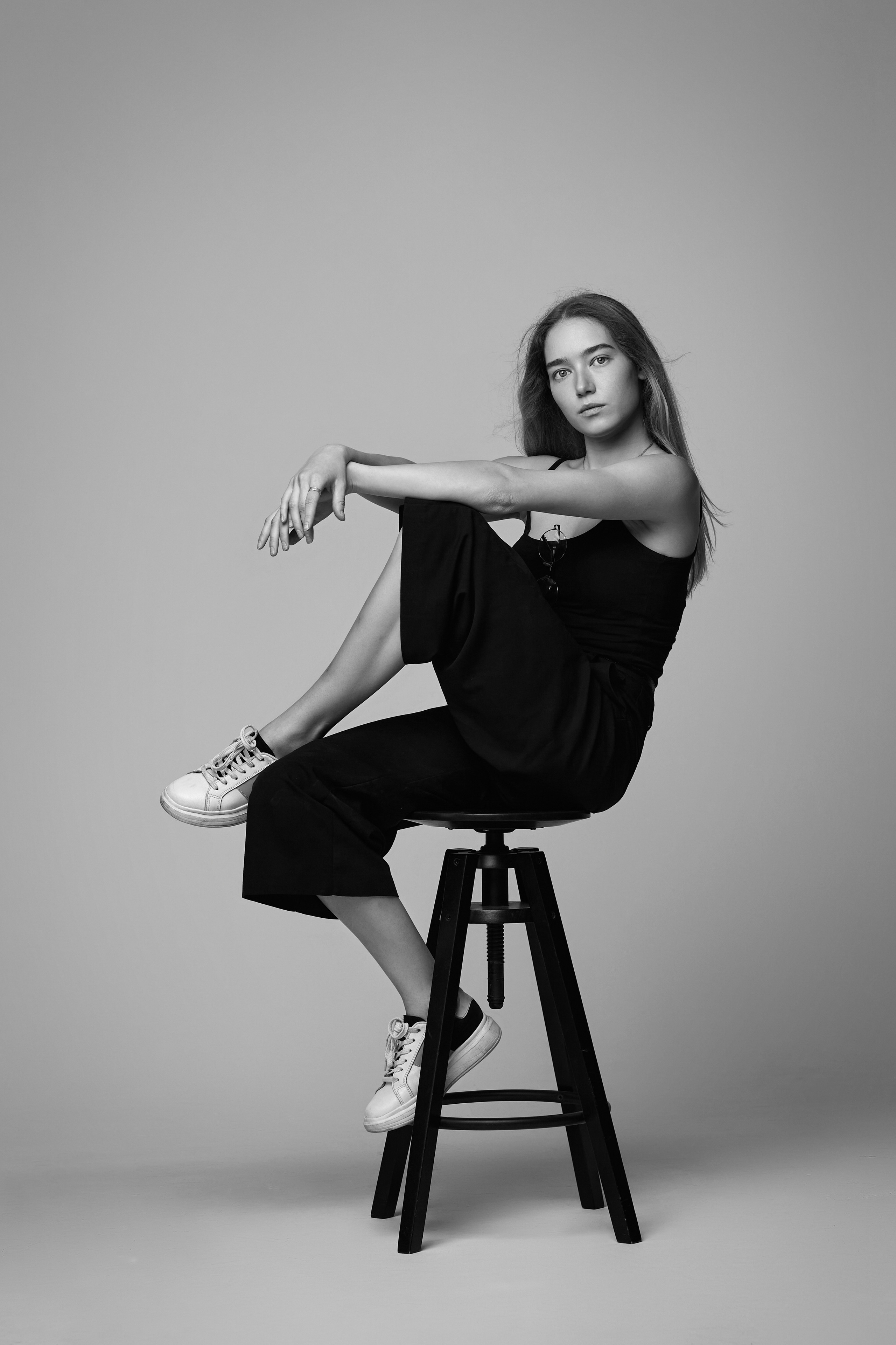 Стильная светловолосая модель Алиса в черной рубашке на светлом фоне студии.