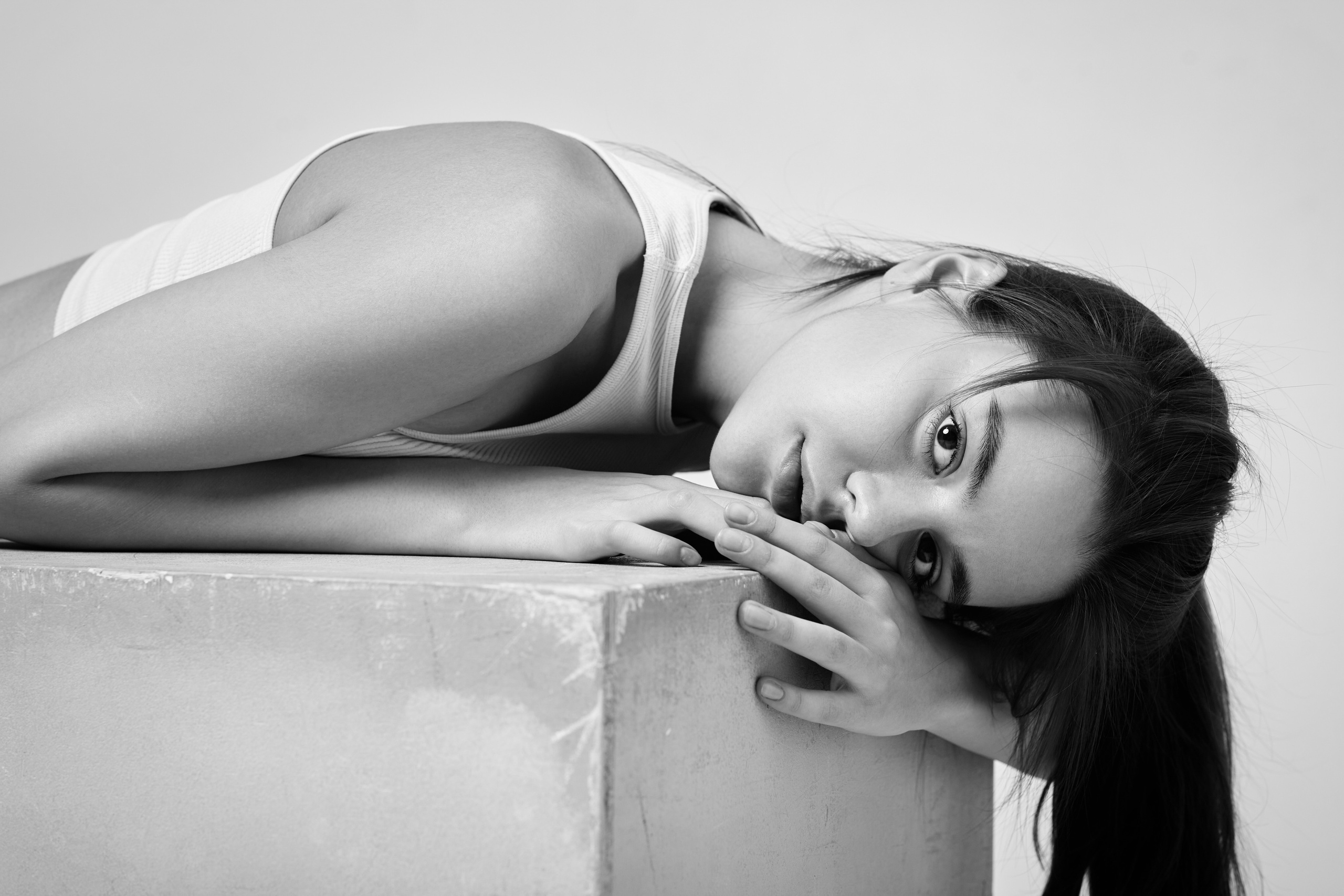 В студии на светлом фоне темноволосая красотка Амина в белом топике и кожаных шортах.