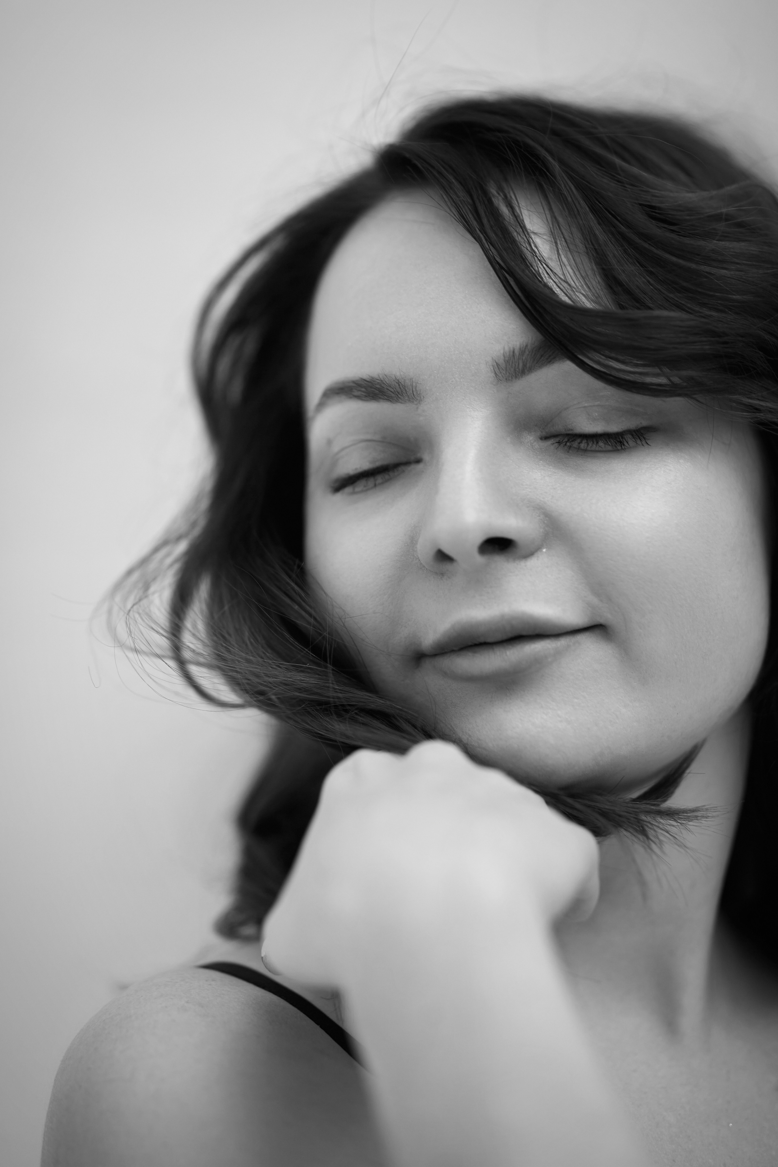 Темноволосая модель Татьяна в рубашке стоит в студии на светлом фоне.