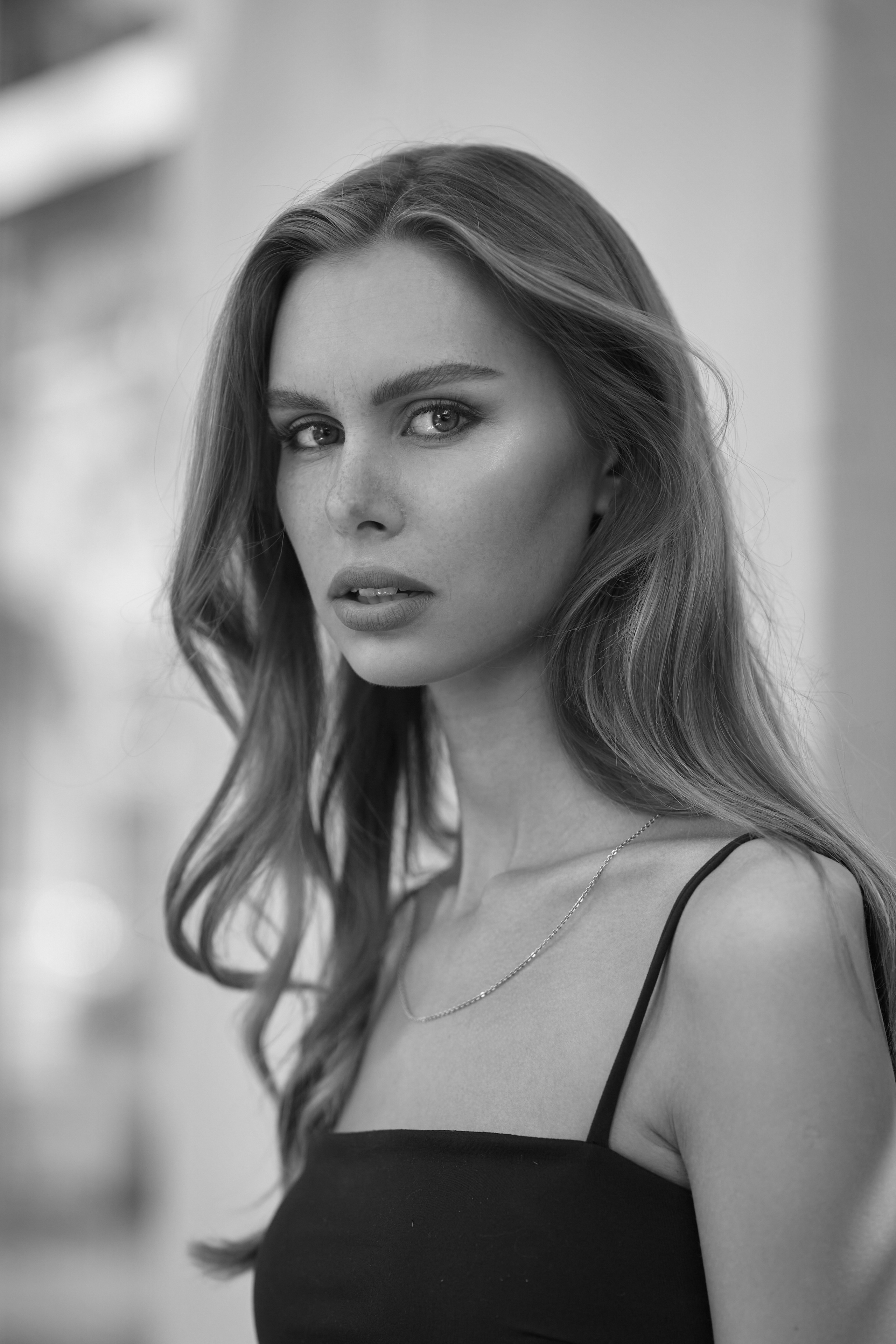 Шляпа и очки придают образу темноволосой девушки на светлом фоне загадочности и таинственности.