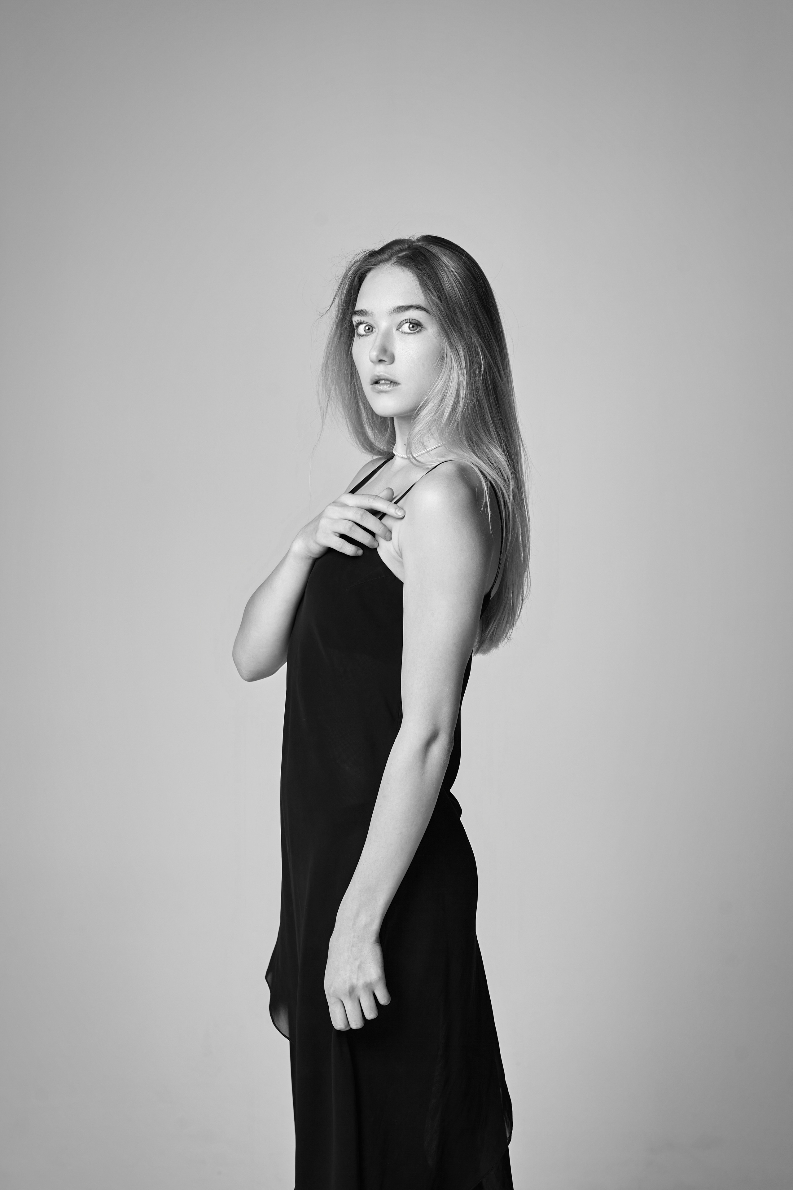 Алиса на светлом фоне в классической белой рубашке и узких джинсах.