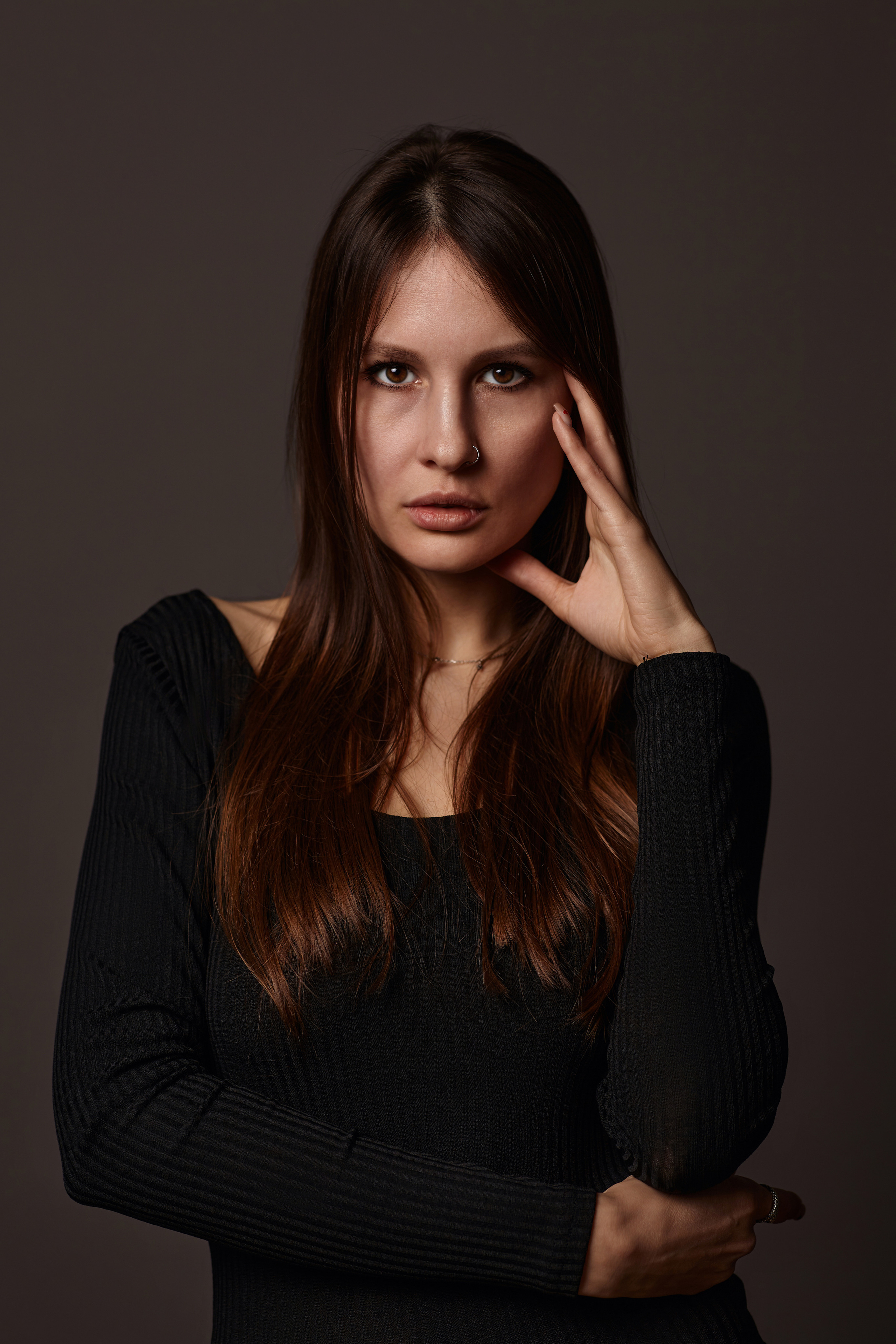 Фото темноволосой модели на темном циклорамном фоне.
