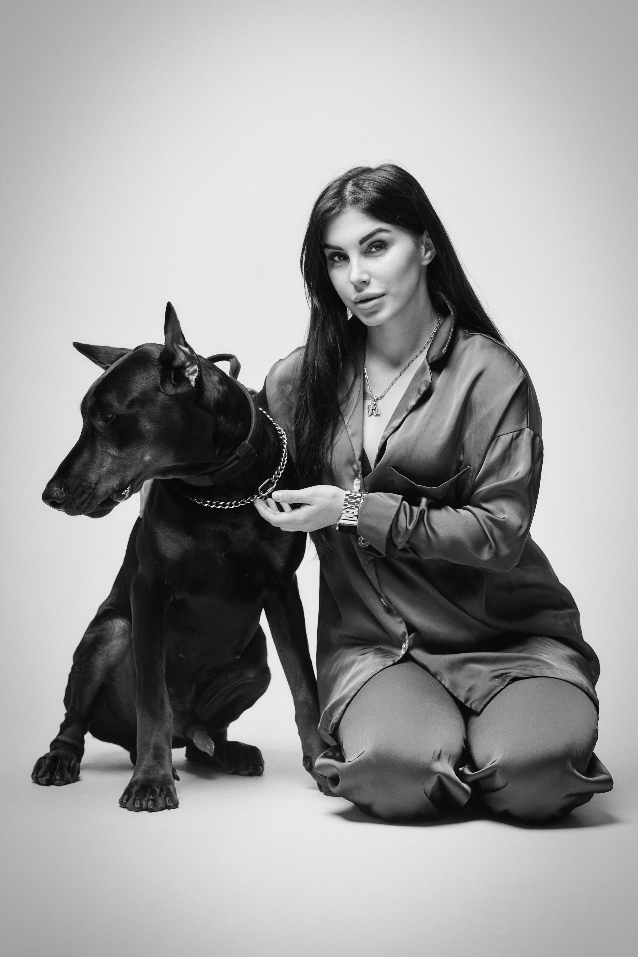 Модель Карина в темном костюме на светлом фоне в студии.