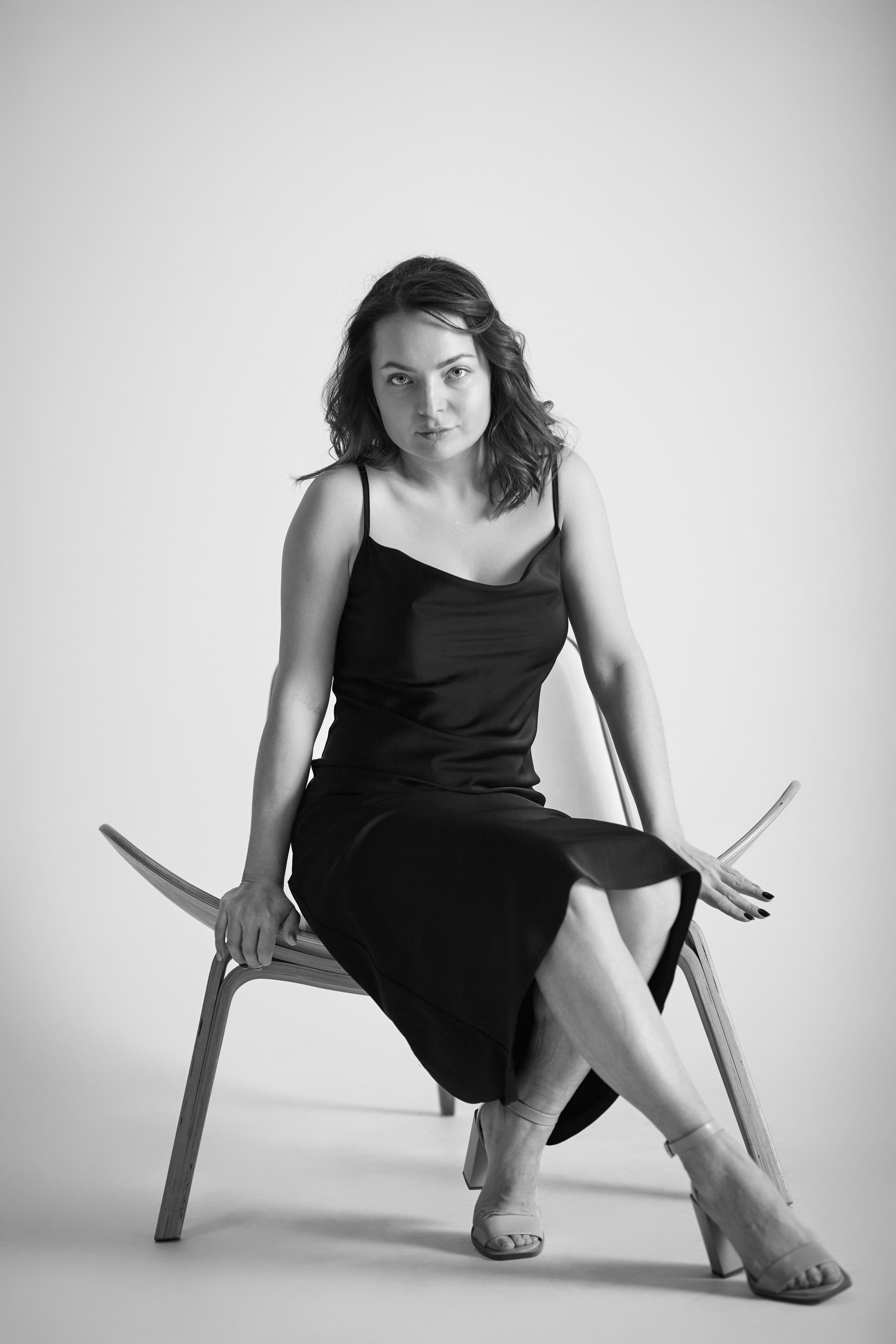 Татьяна, сидящая на стуле в студии, в светлом наряде.