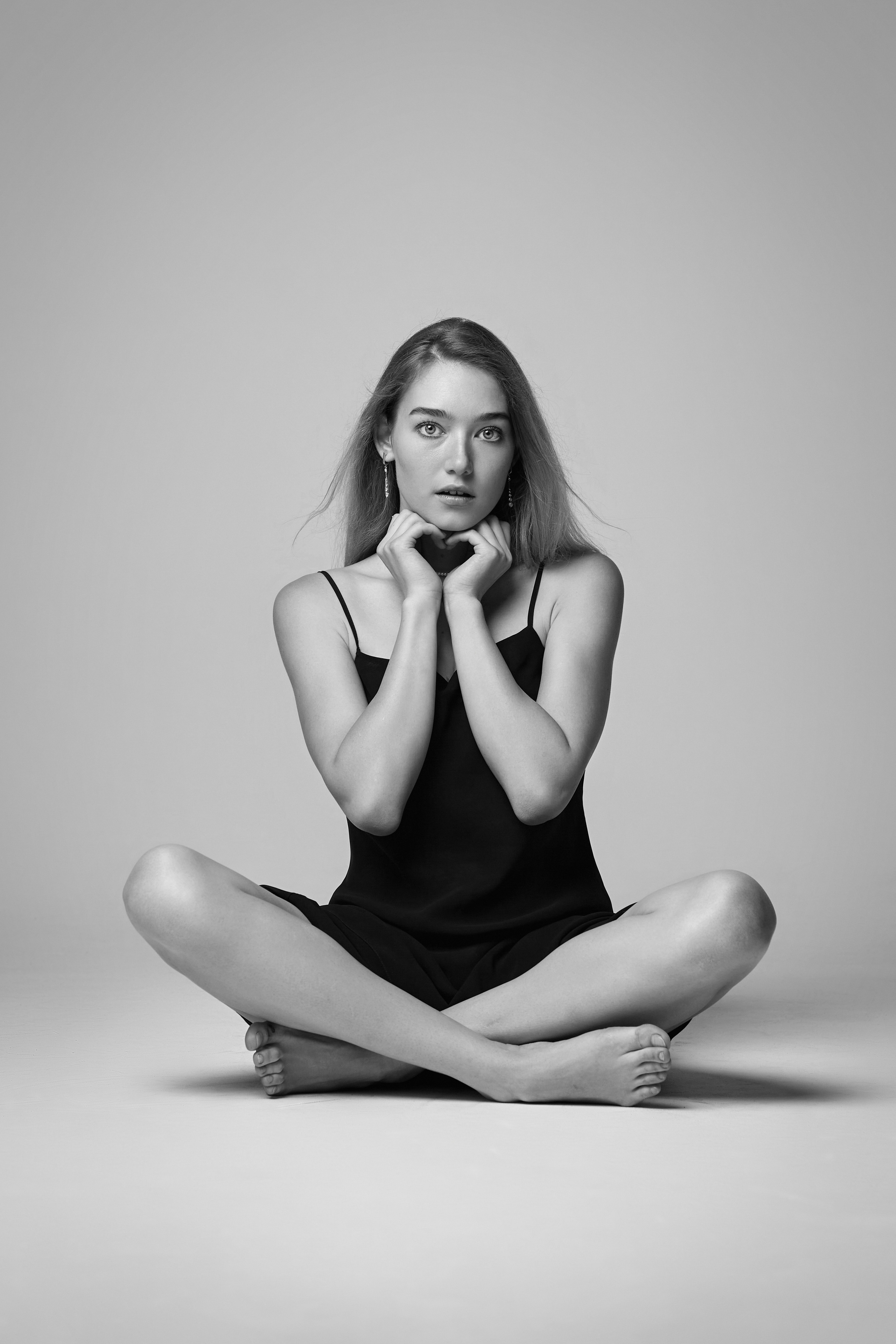 На светлом фоне студии, светловолосая модель Алиса позирует в своей белоснежной рубашке.