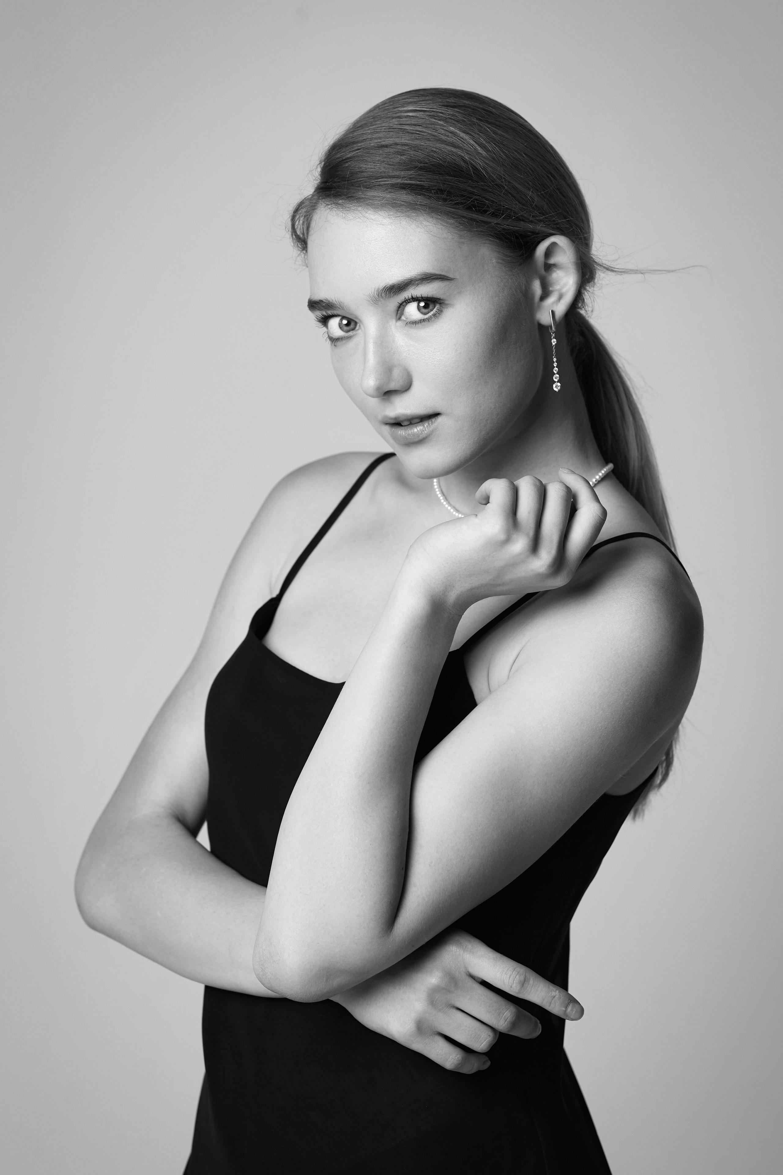 Алиса, модель с прекрасной фигурой, в свободной рубашке на светлом фоне студии.