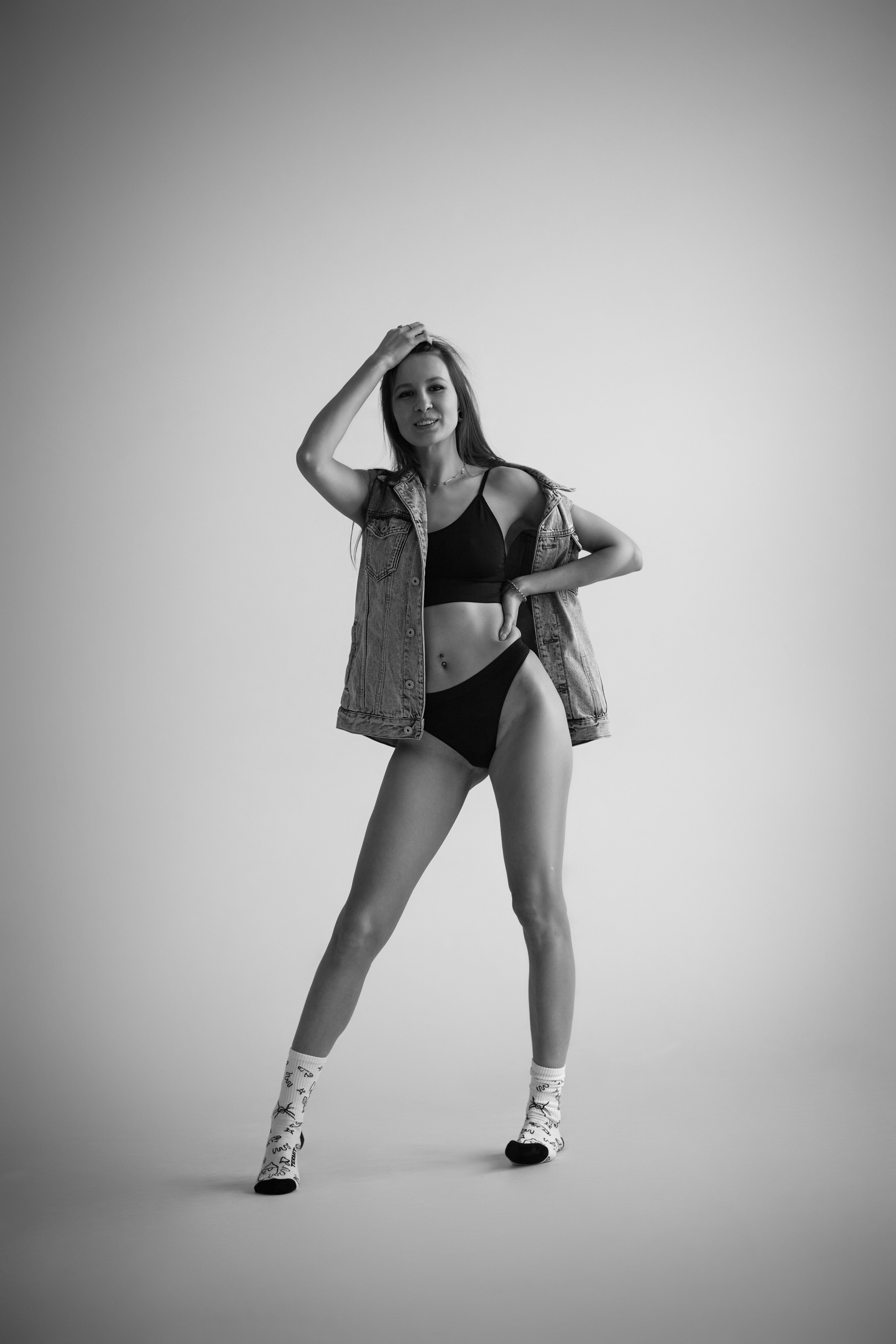 Красивая темноволосая девушка позирует в студии на темном фоне, подчеркивая свои изящные черты лица