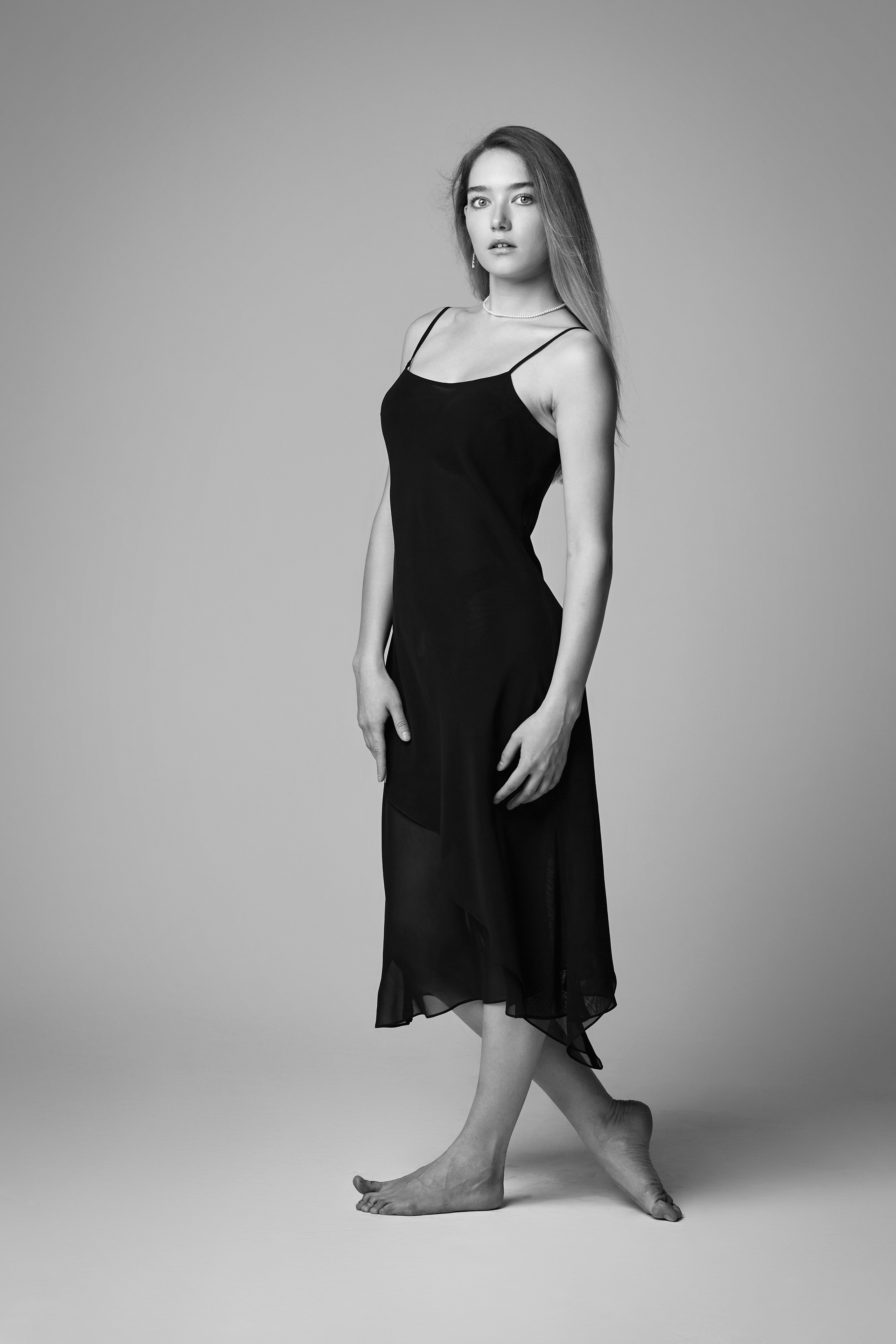 Алиса, светловолосая модель в платье, фотографируется на светлом фоне студии.