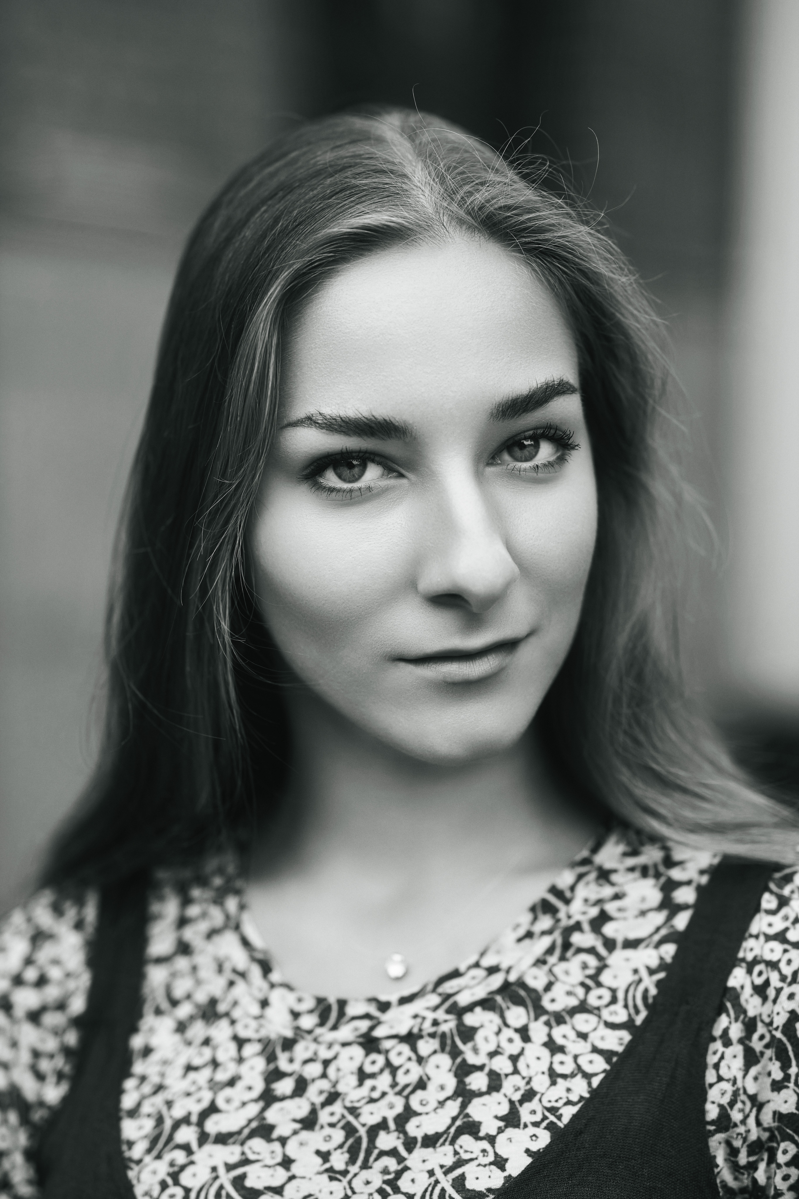 Любовь - модель с темными волосами, прогуливается по городу в стильном платье, приковывая к себе внимание.