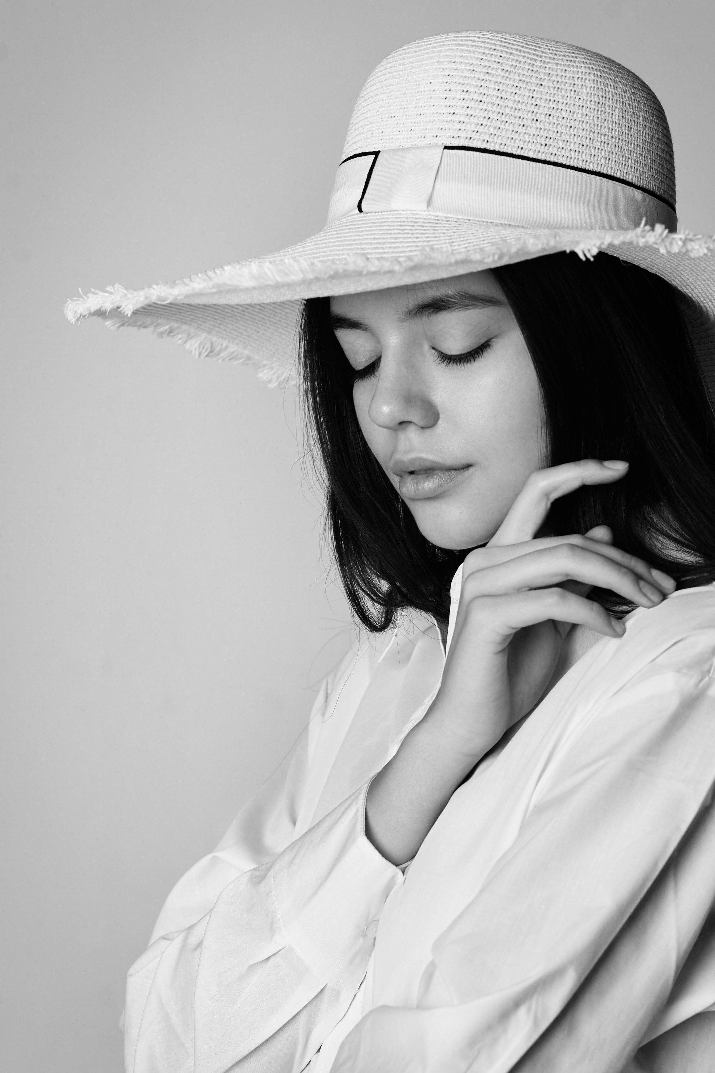 Темноволосая модель Амина на светлом фоне в белой рубашке и короткой джинсовой юбке.