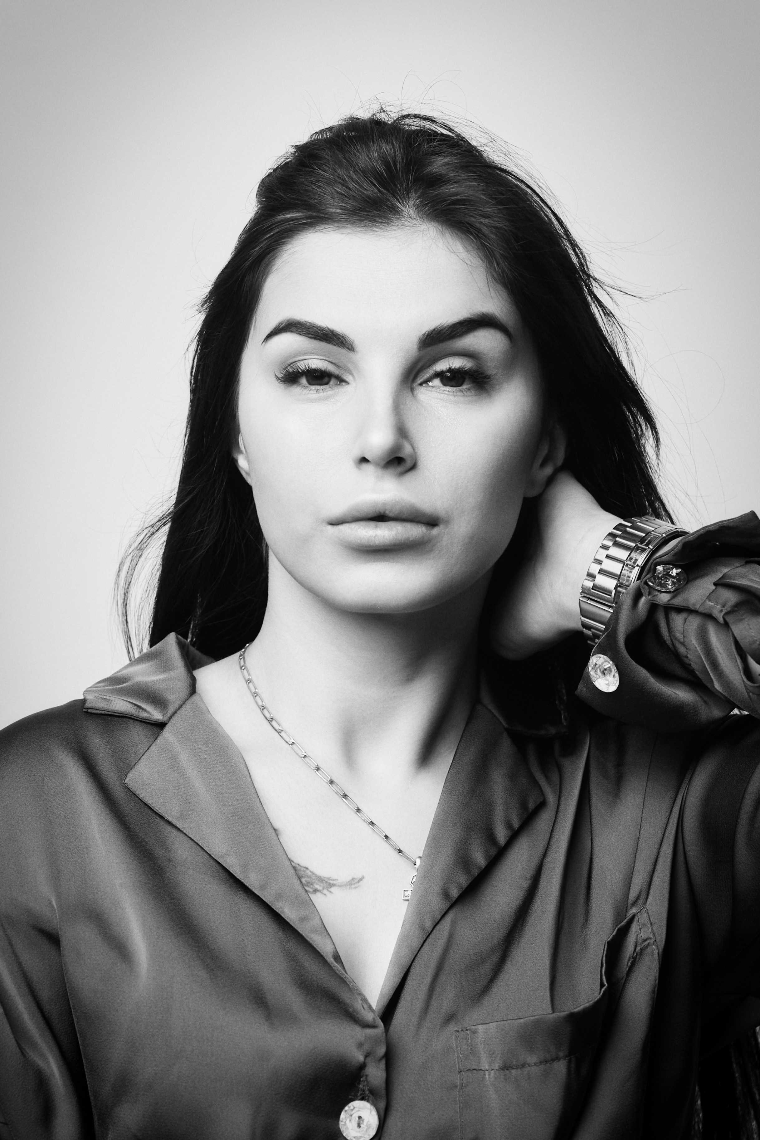 Темноволосая модель Карина в костюме на светлом фоне в профессиональной студии.