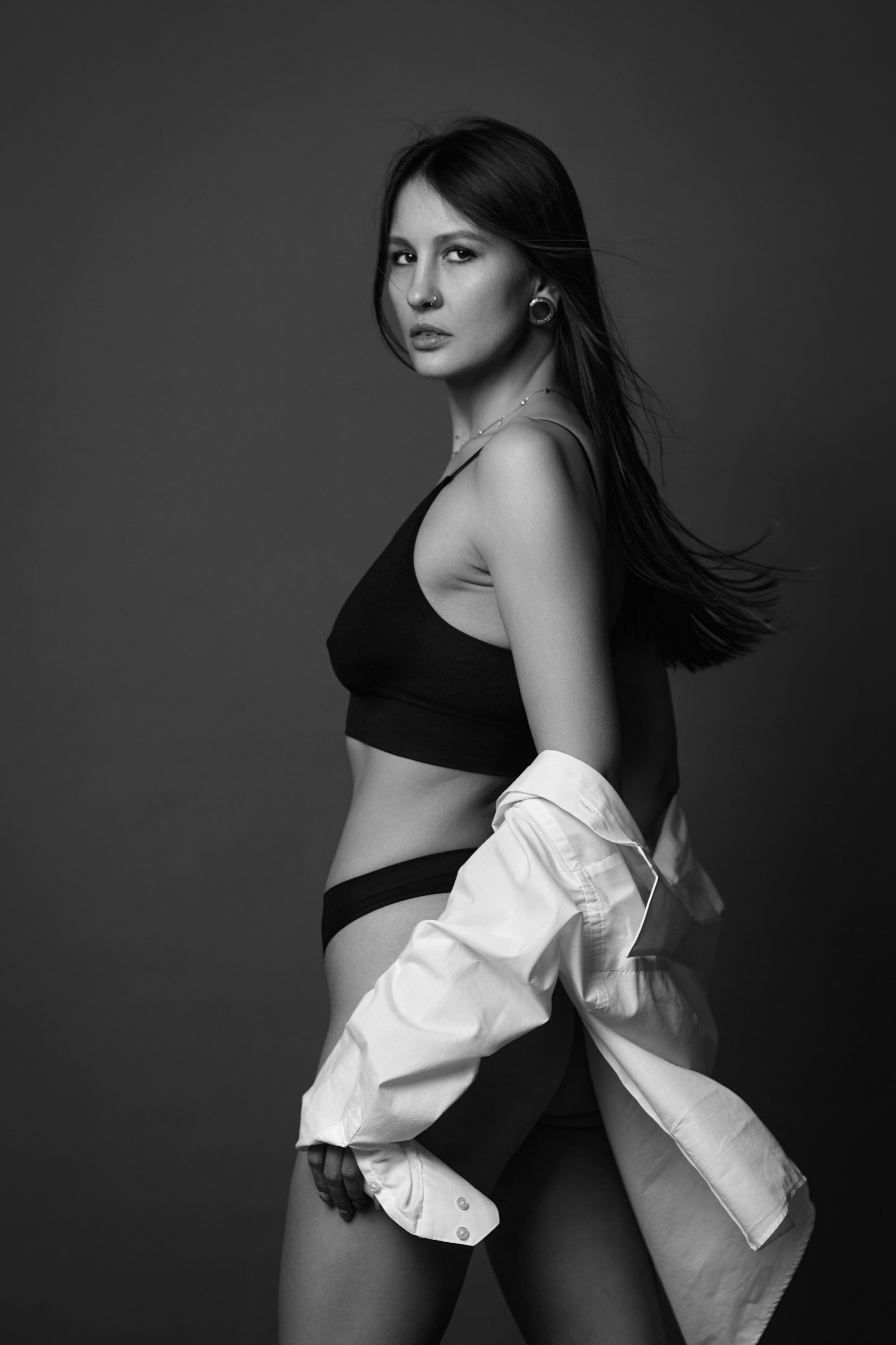 Темноволосая девушка на циклораме с светлым фоном демонстрирует свой образ.