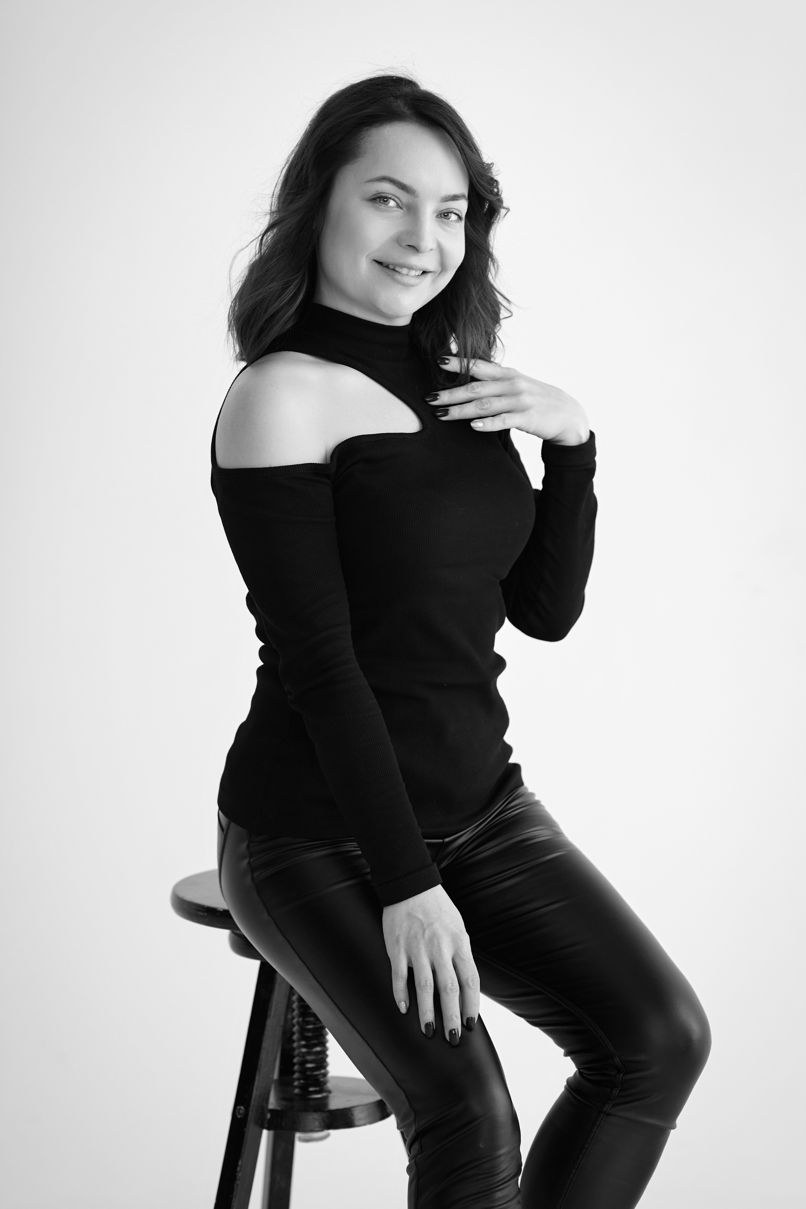 Сидя на стуле в студии на светлом фоне, Татьяна одета в светлое платье.