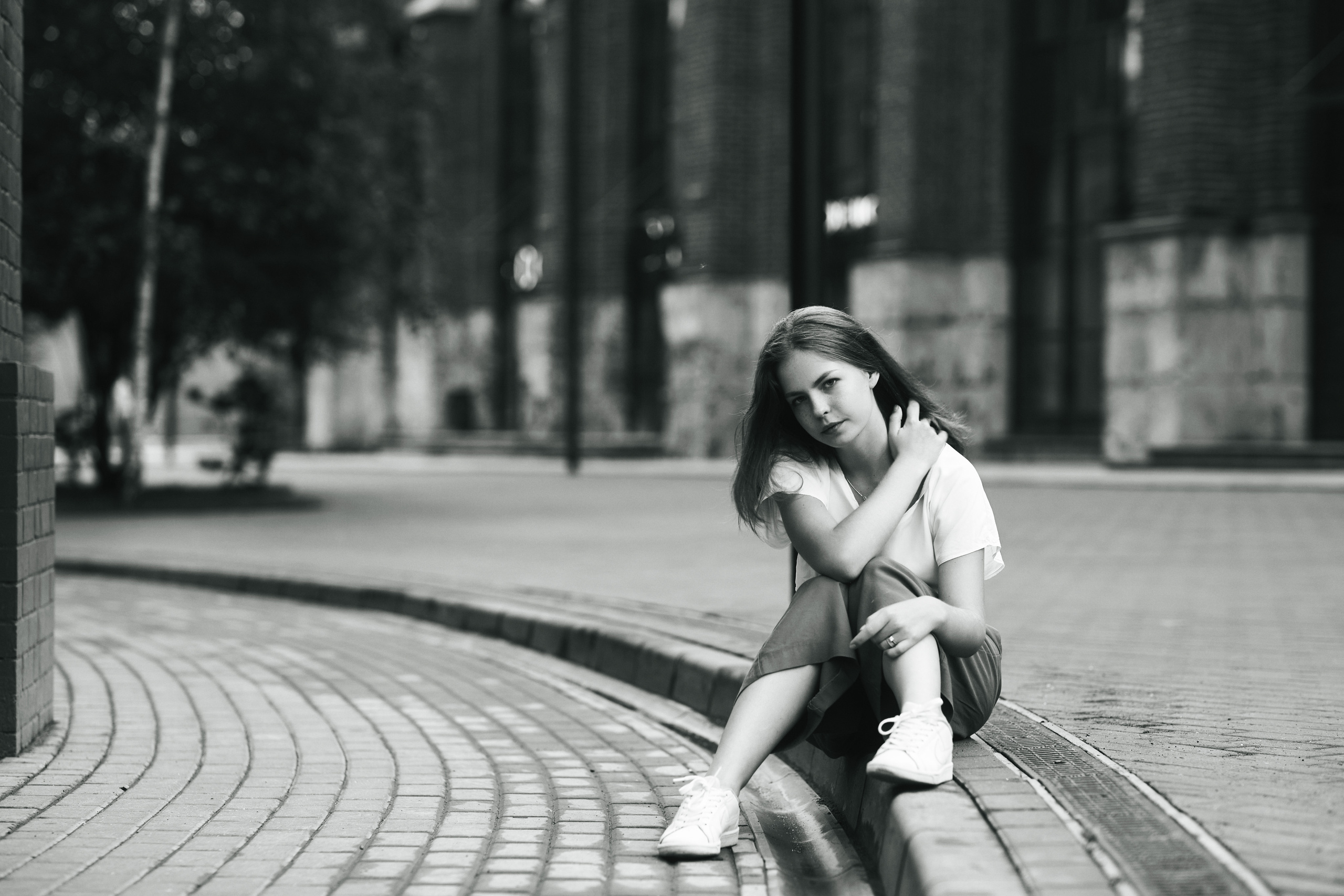 Темноволосая модель Дарья на фоне города Москвы в светлой кофте и широких брюках.